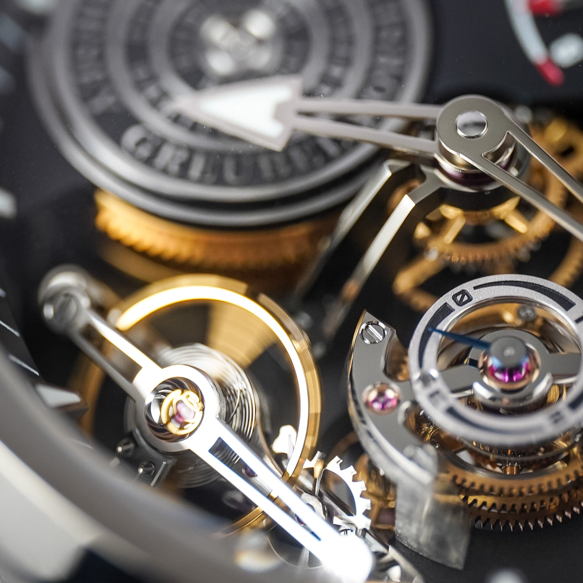 Extreme close-up of a mechanical watch movement with visible gears, bridges, screws, and polished metal components in silver and gold tones.