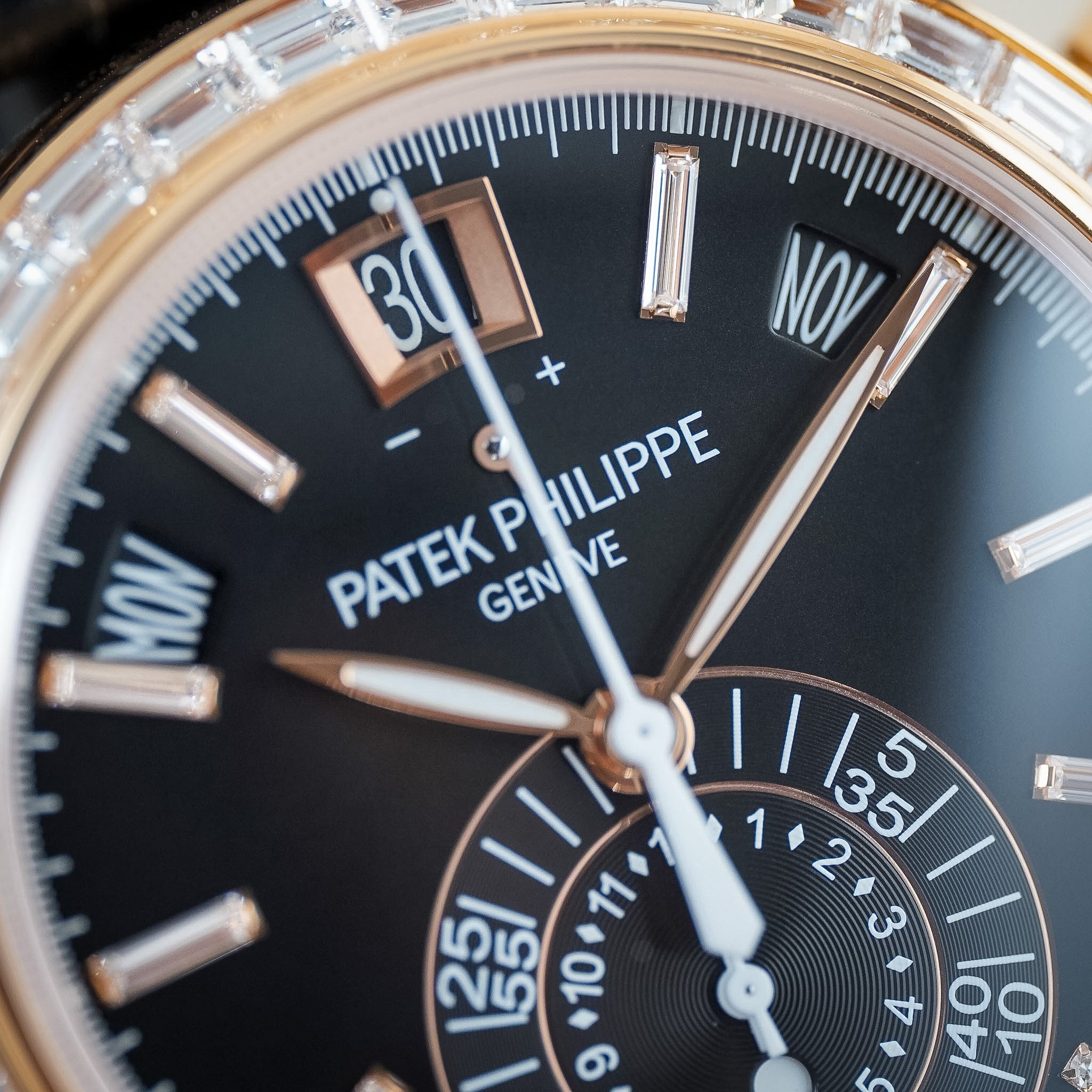 Close-up of a Patek Philippe wristwatch with a black dial, rose gold-toned markers and hands, and a bezel set with clear baguette stones.