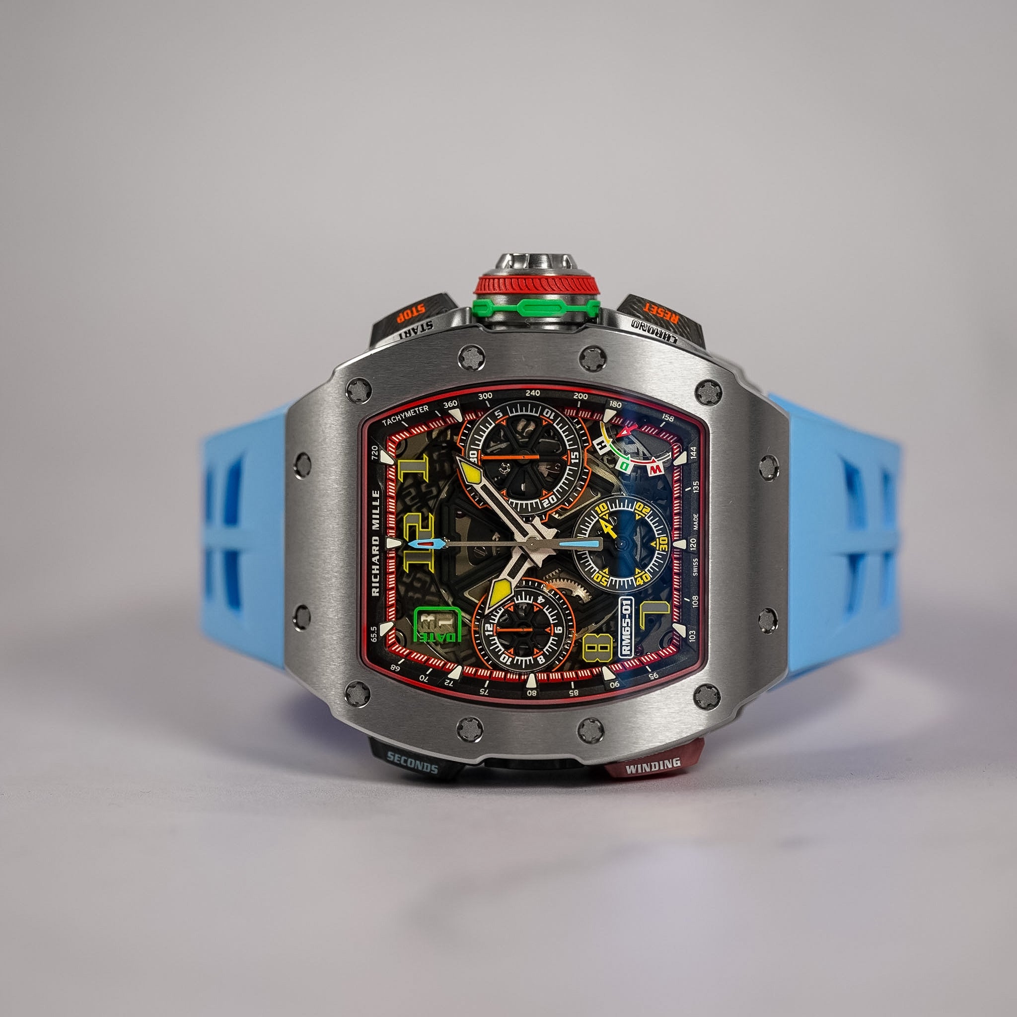 A custom-built chronograph watch featuring a silver titanium case, a vibrant multicolor dial with graphic elements, and a light blue silicone strap, photographed against a neutral gray background.