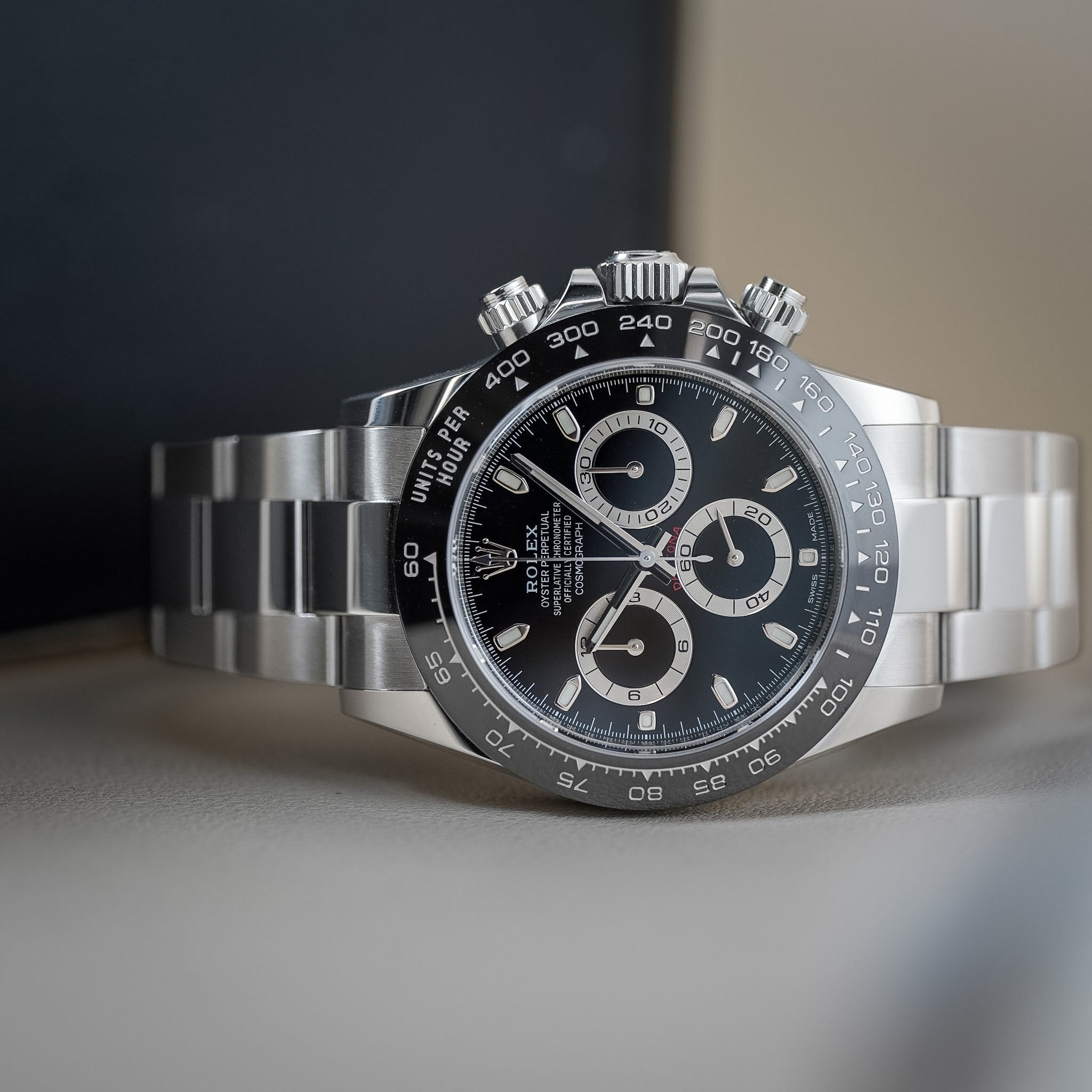 A Rolex Cosmograph Daytona wristwatch with a stainless steel Oyster bracelet, featuring a black dial, silver-tone bezel, and three subdials.