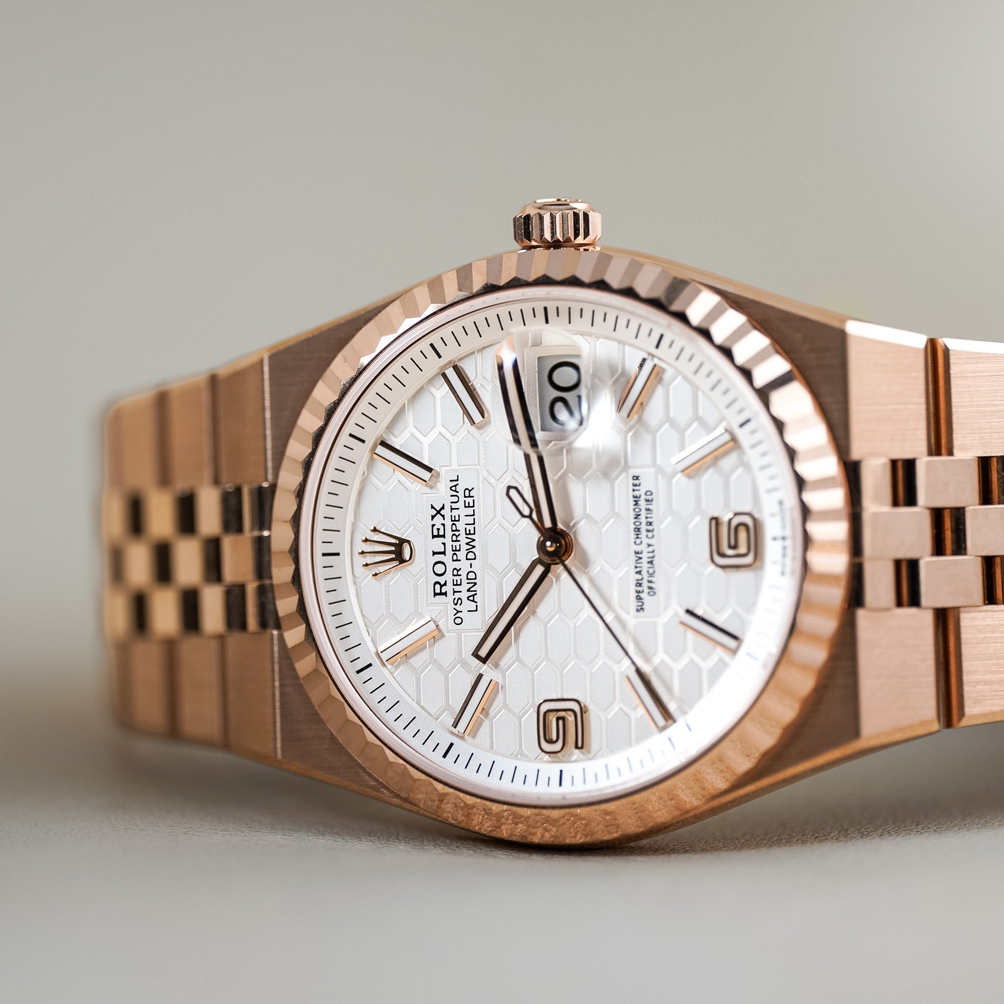 Rolex Gold-Diver watch with a rose gold case and bracelet, featuring a white dial with a subtle honeycomb pattern and a date window.