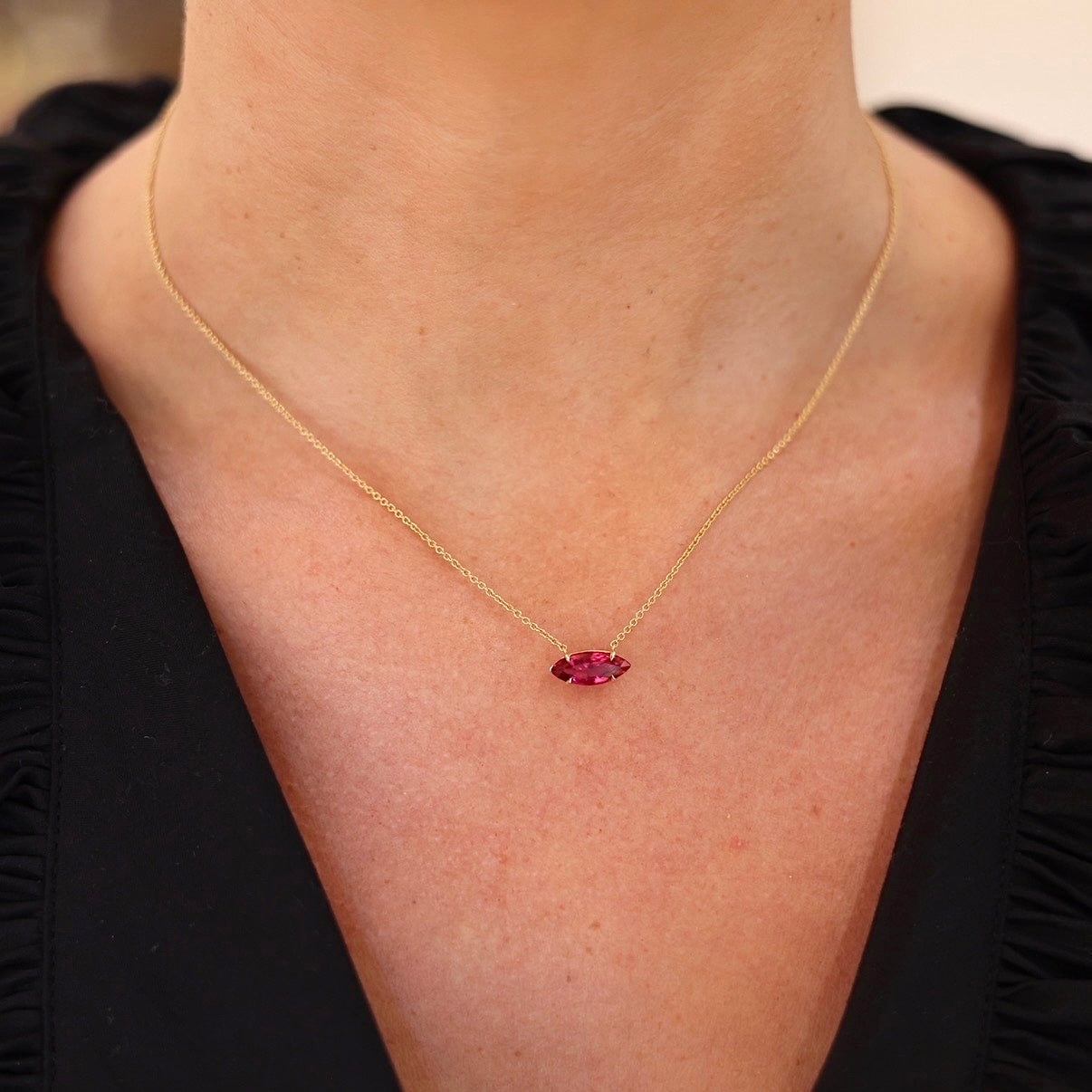 Marquise ruby pendant necklace in 14K rose gold with a four-prong basket setting on a delicate chain on figure