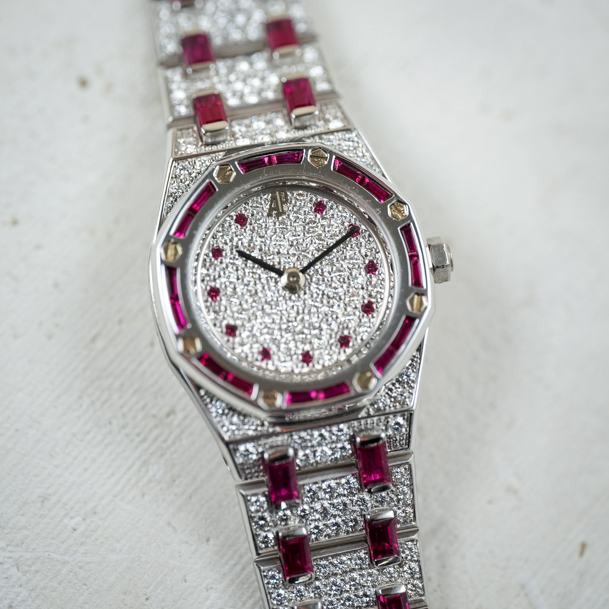 Luxury watch with diamond and ruby accents on a light background