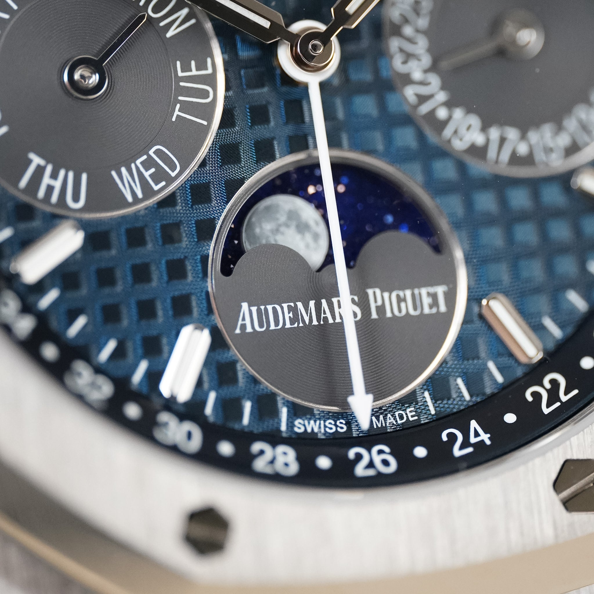 Closeup of an Audemars Piguet wristwatch with a moonphase subdial and a textured blue dial. 