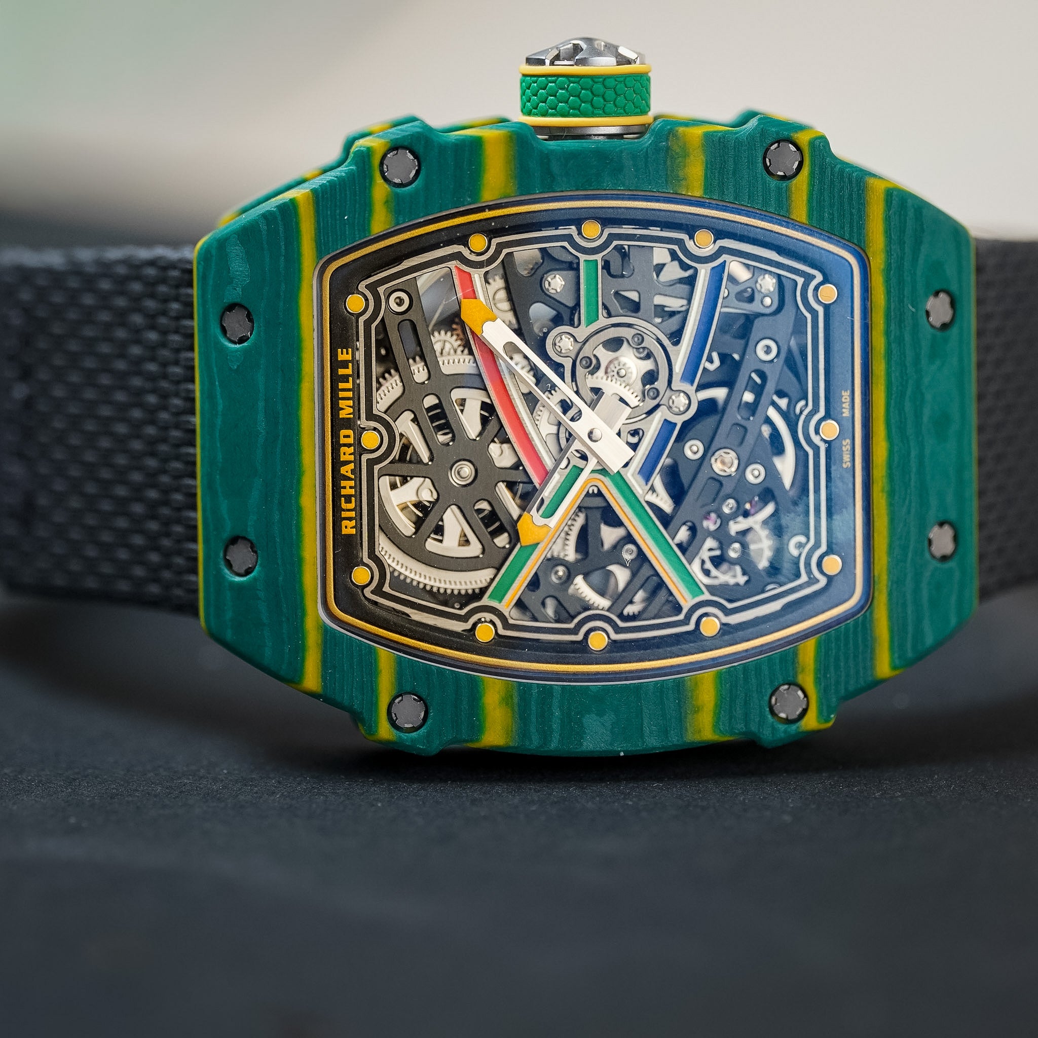 Richard Millier wristwatch with a distinctive green and yellow striped carbon fiber case, featuring a skeleton dial with multicolored hands and visible mechanical gears.