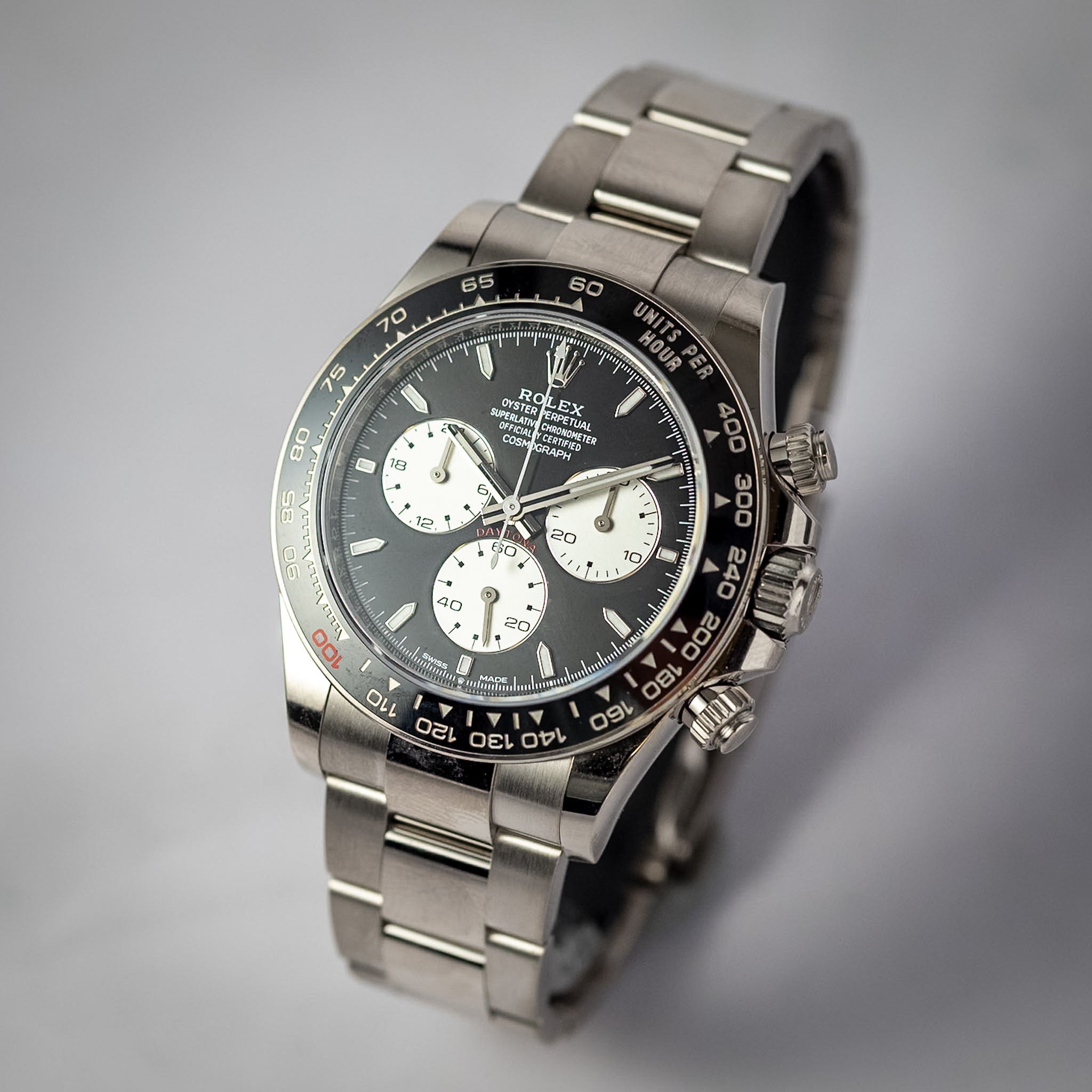A Rolex Daytona wristwatch with a stainless steel bracelet, featuring a black dial with white subdials and a black tachymeter bezel.