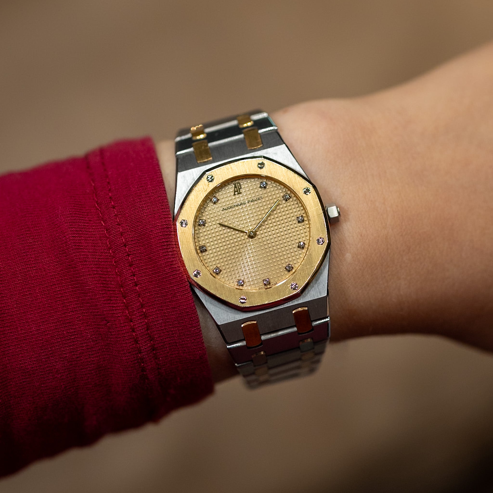 Luxury watch with gold face and silver case on a wrist against a blurred background
