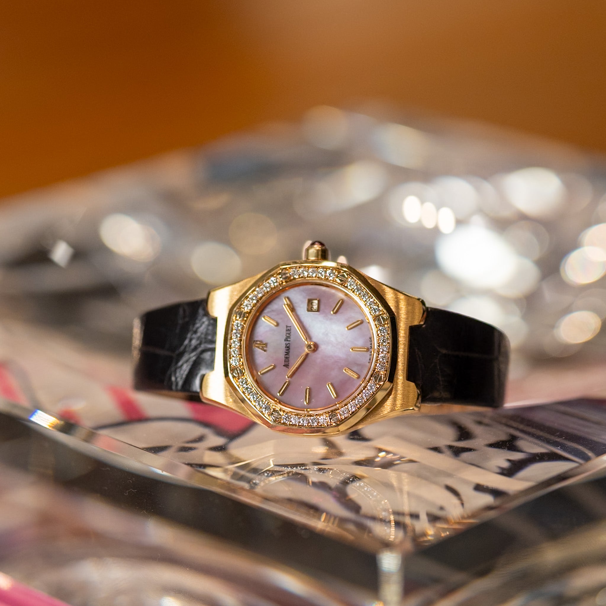 Gold watch with a pink face on a decorative surface