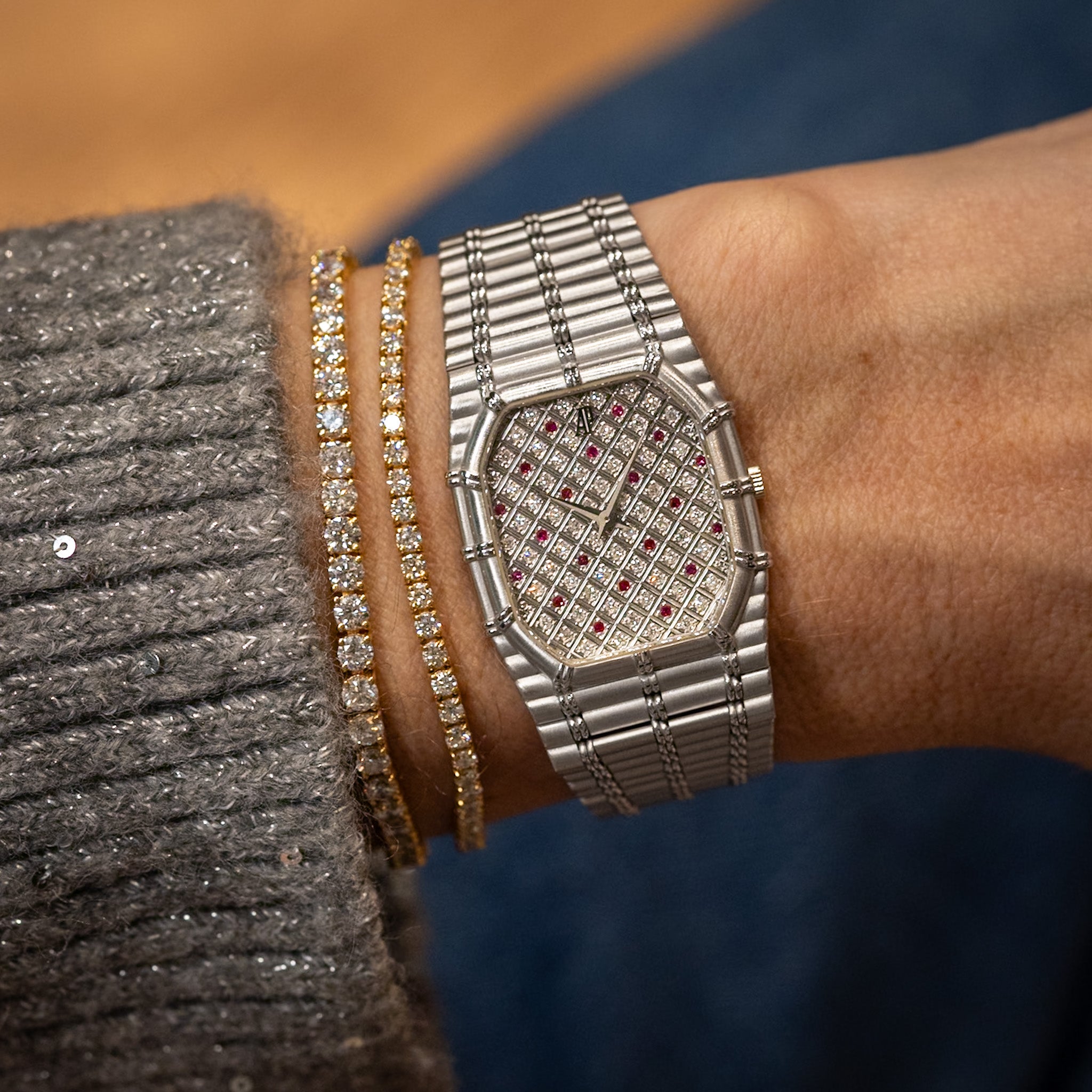 Silver watch with gemstone accents on a wrist against a blurred background