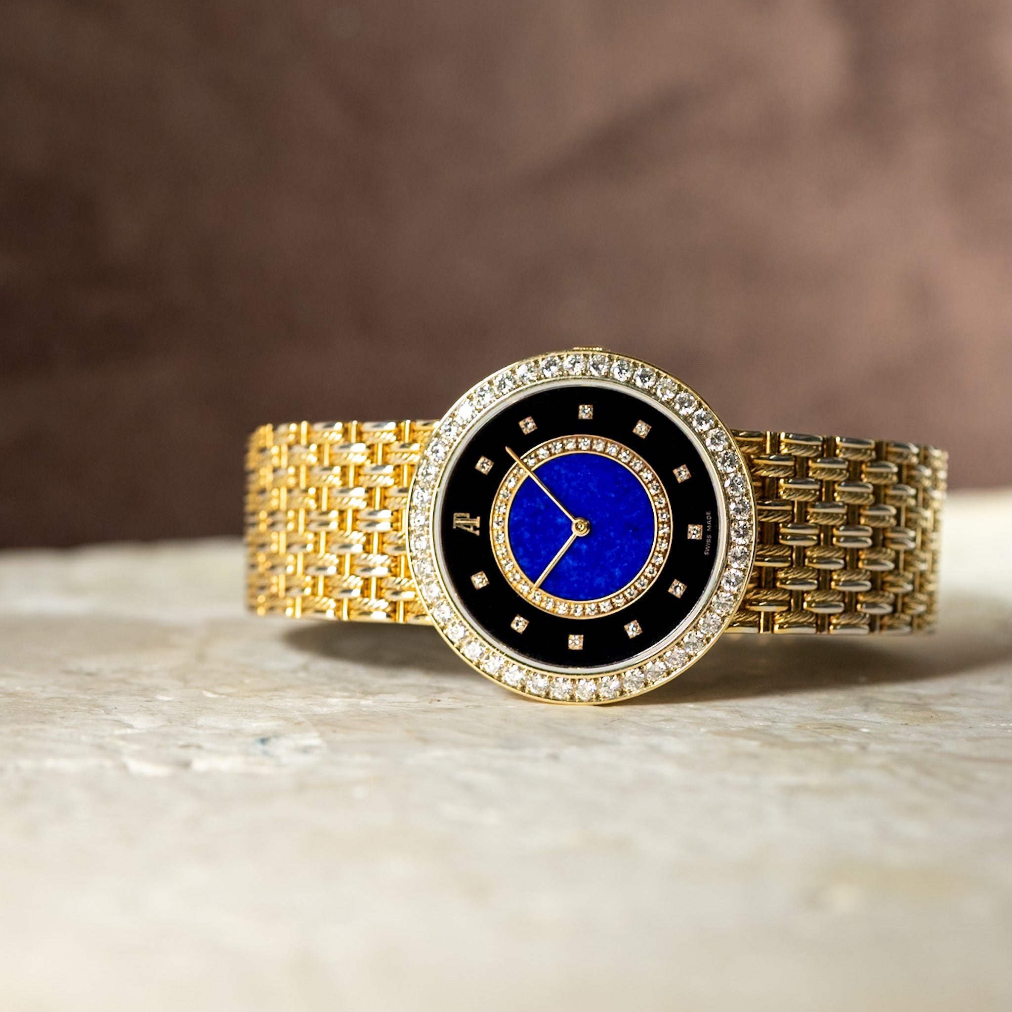 Gold watch with a blue face on a marble surface