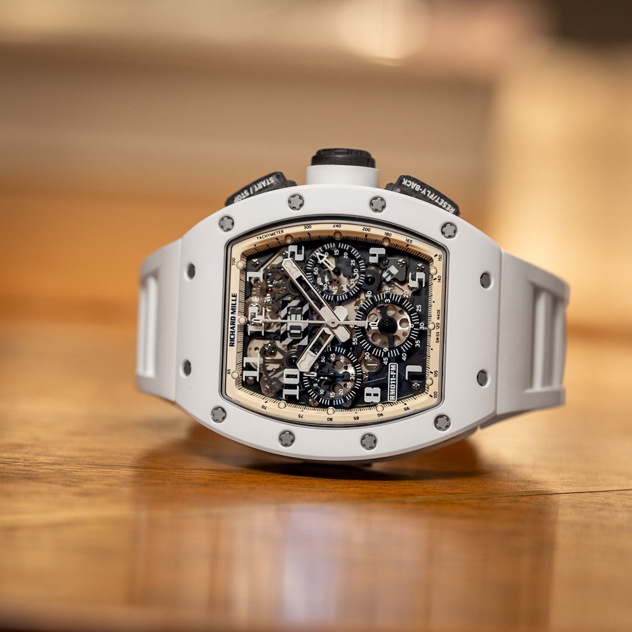 Luxury watch with a white case and black face on a wooden surface