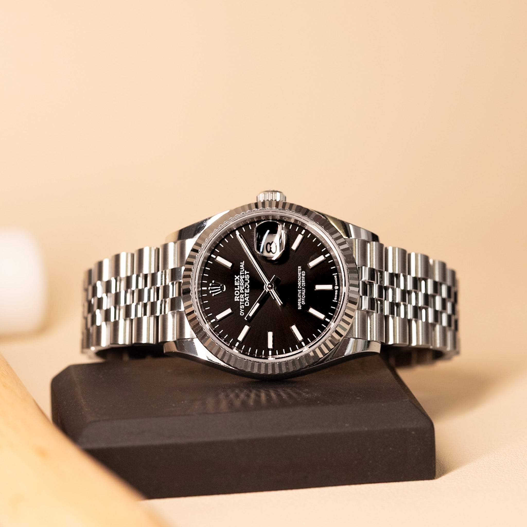 Silver watch with a black face on a beige background