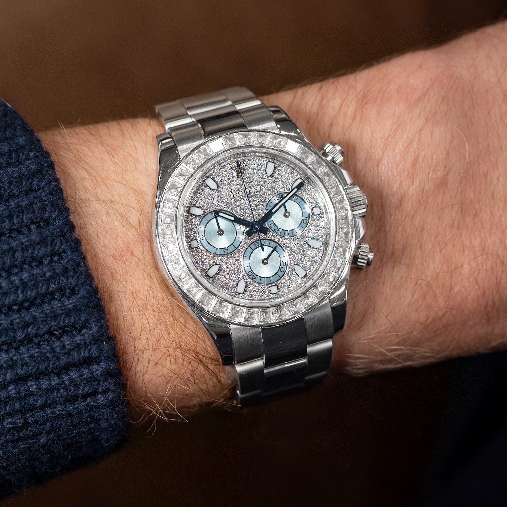 Silver wristwatch with diamond accents on a person's wrist against a dark background