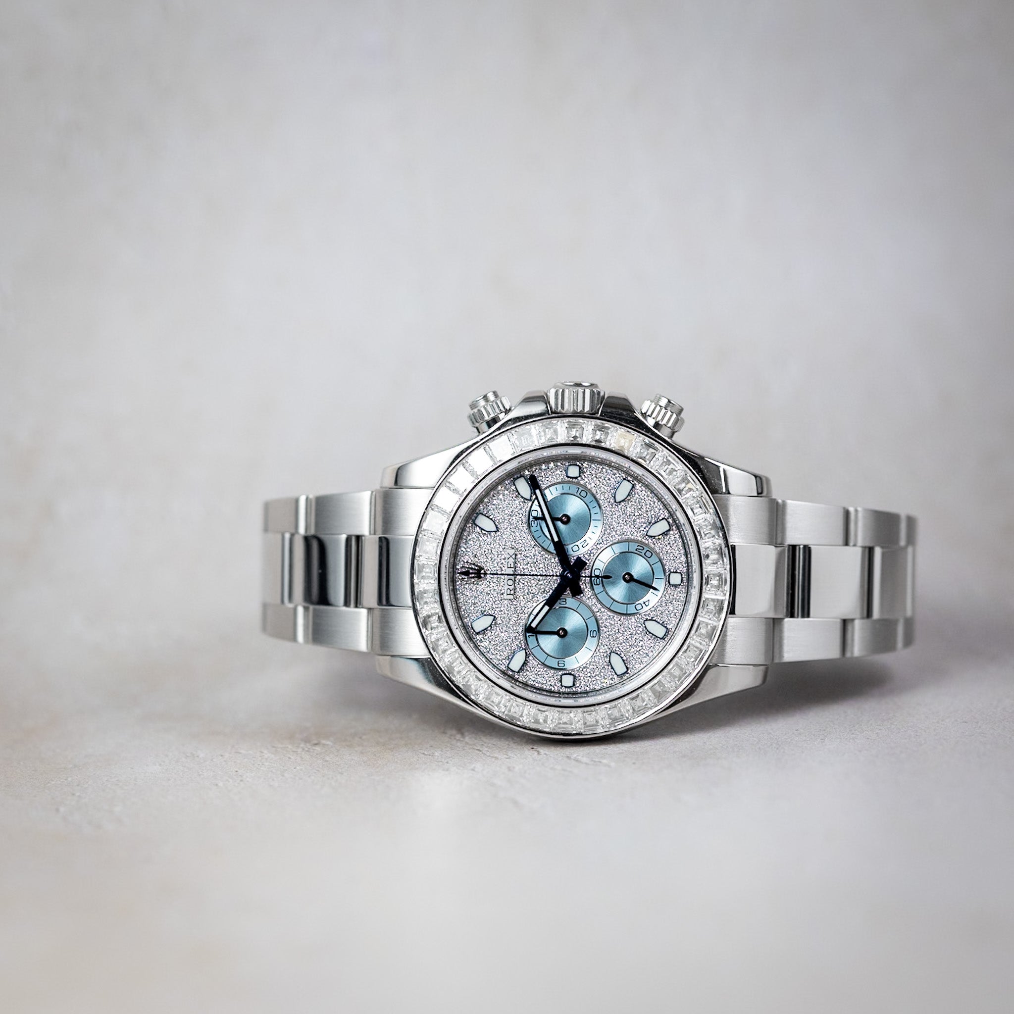 Silver watch with diamond-studded face on a light gray background