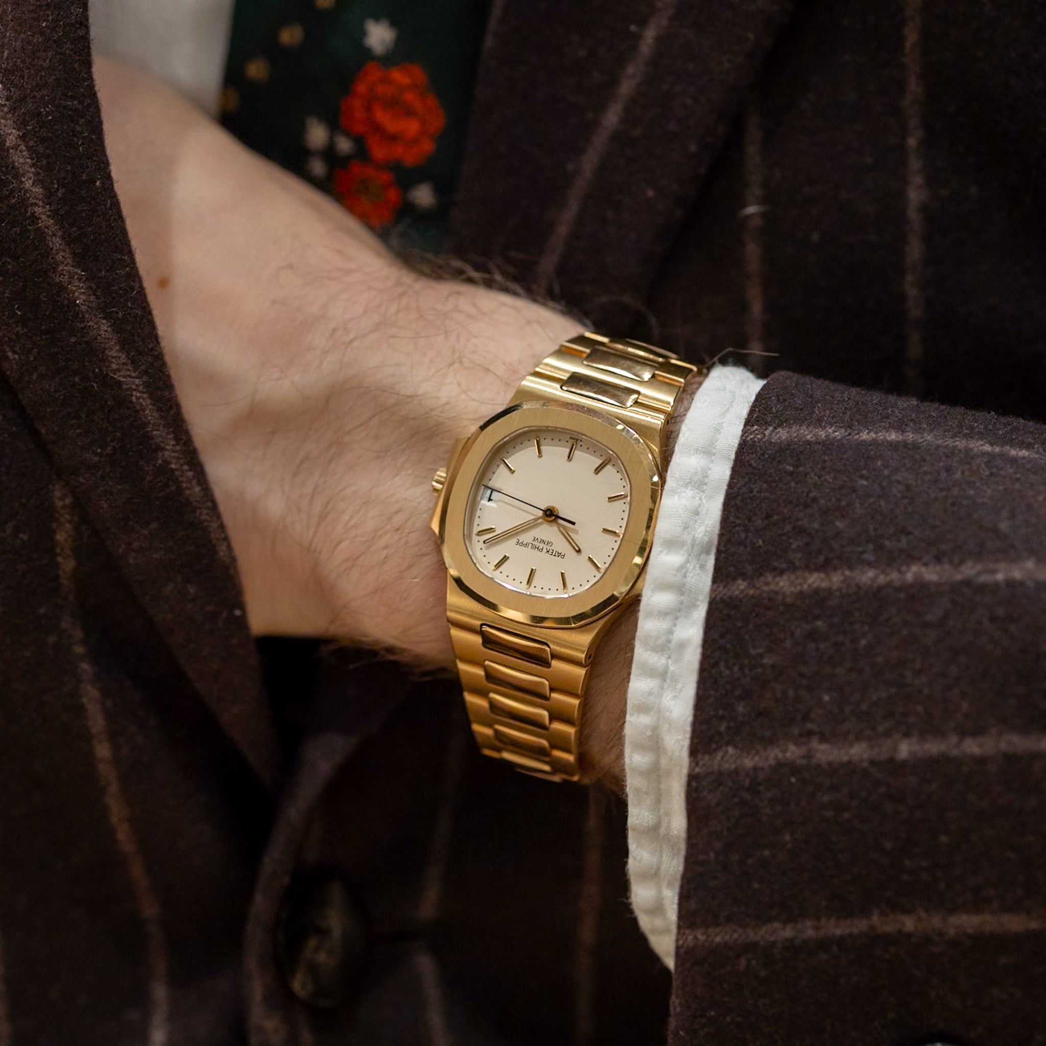 Gold wristwatch on a person's wrist with a dark background