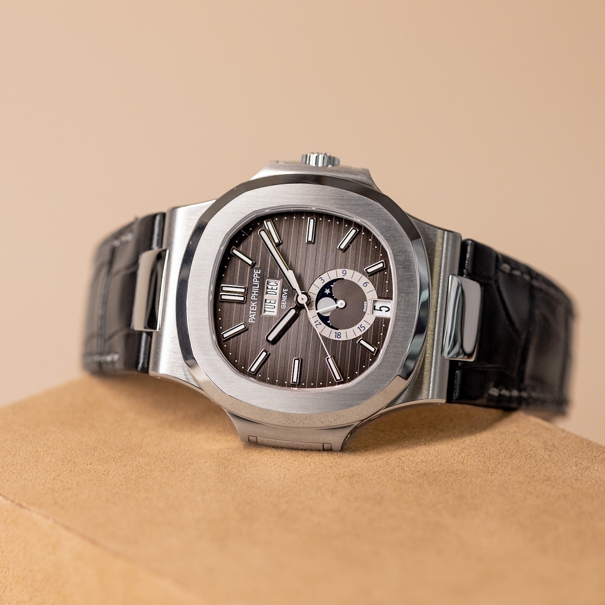 Luxury watch with a brown dial and black strap on a beige background