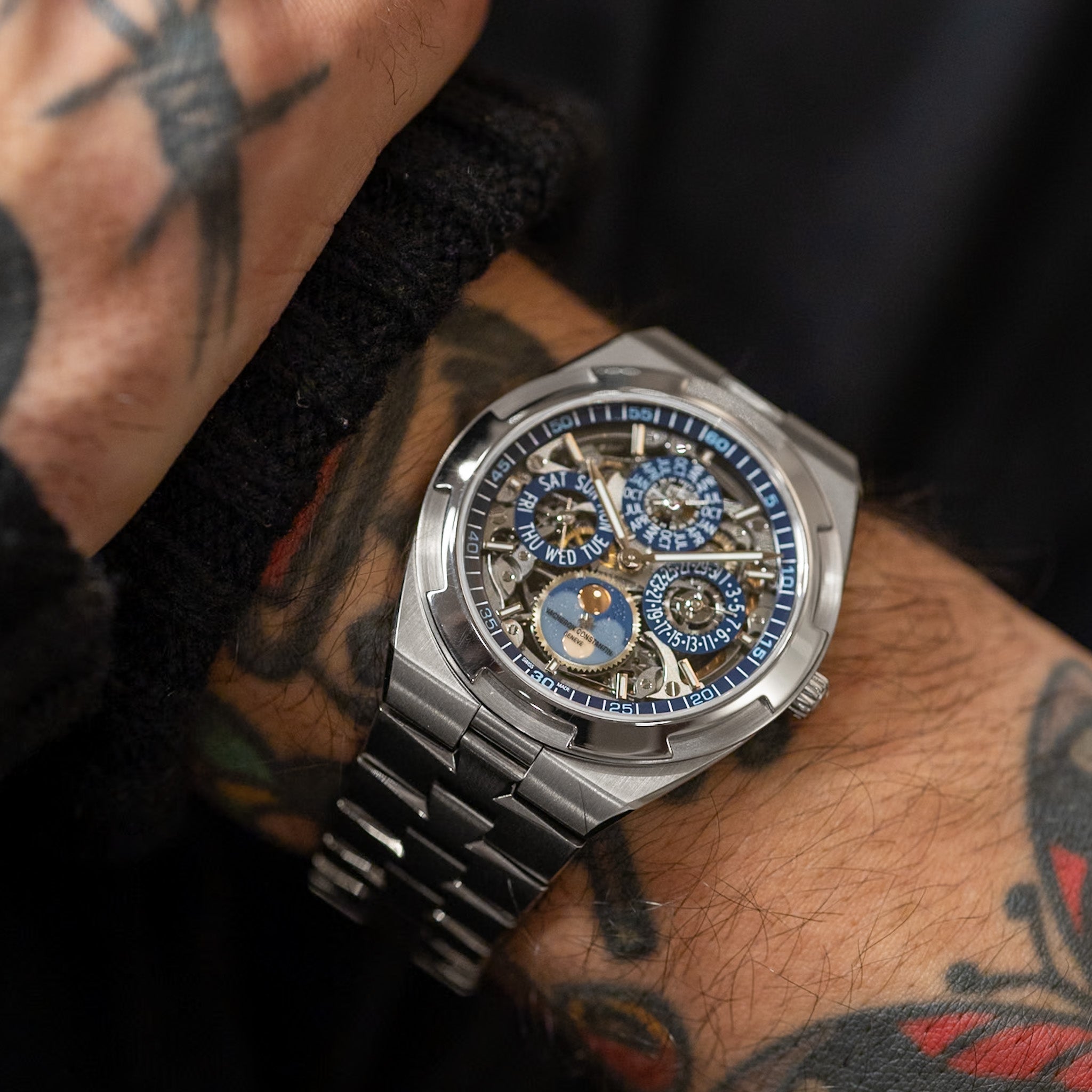 Silver wristwatch with a detailed face on a tattooed arm