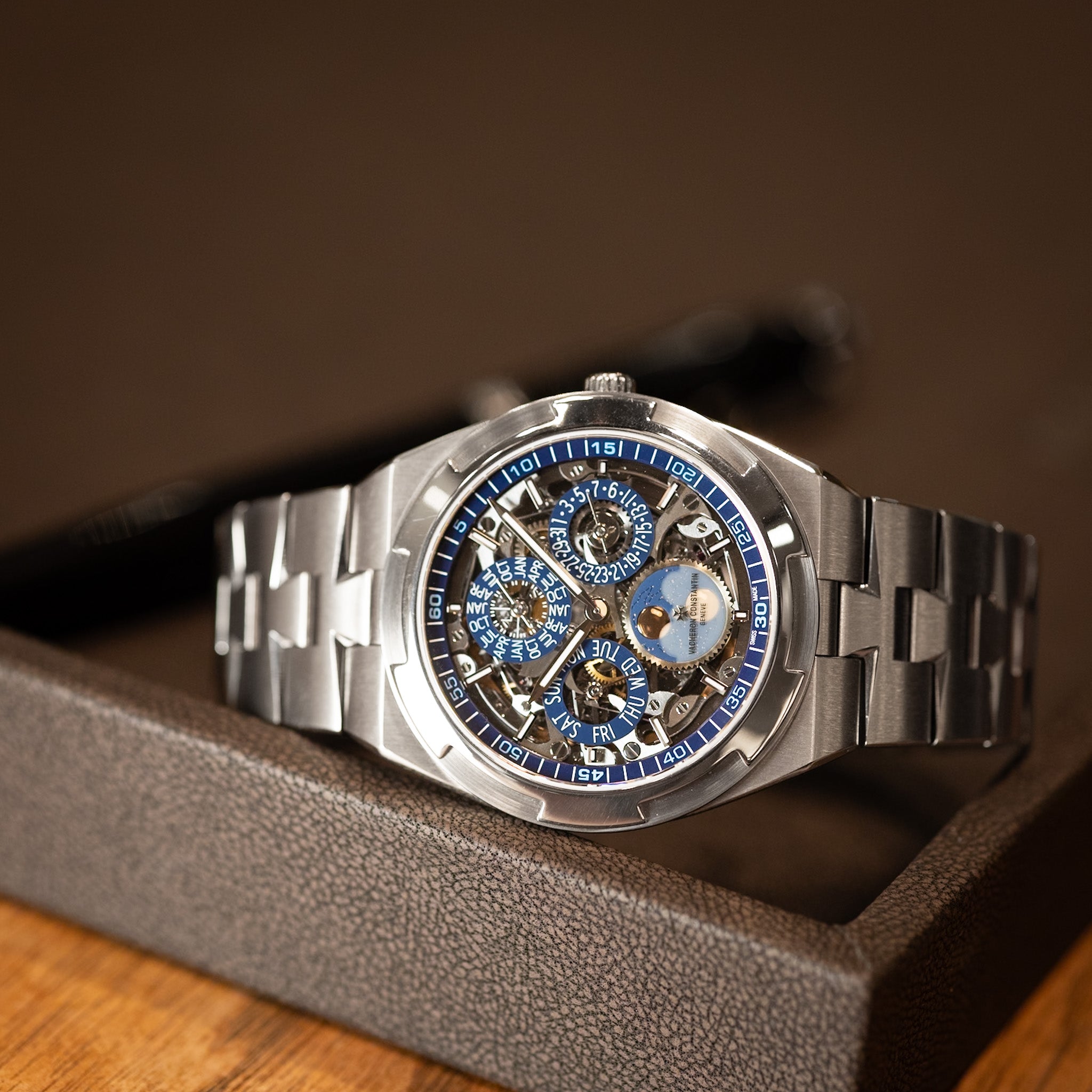 Silver wristwatch with blue accents on a wooden surface