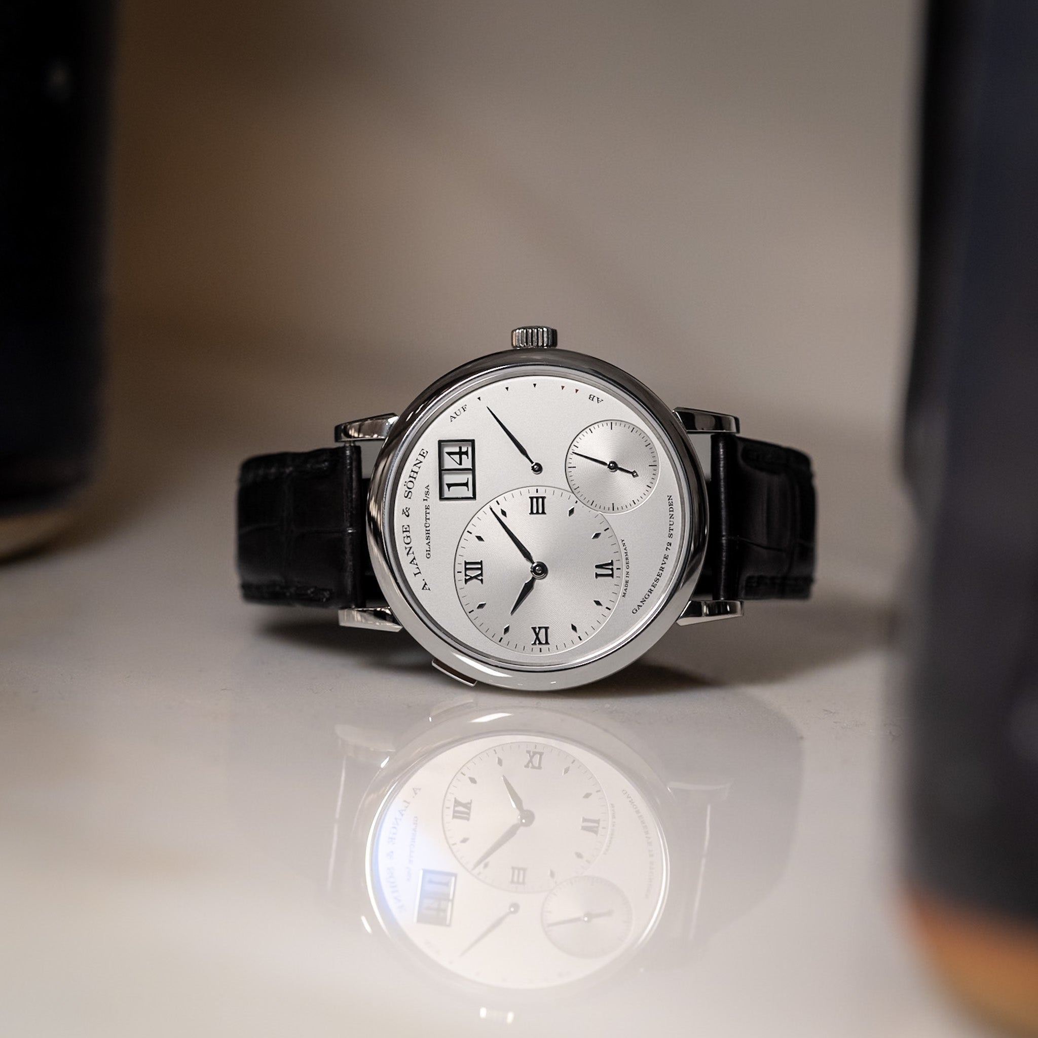 Luxury watch with a black strap on a reflective surface