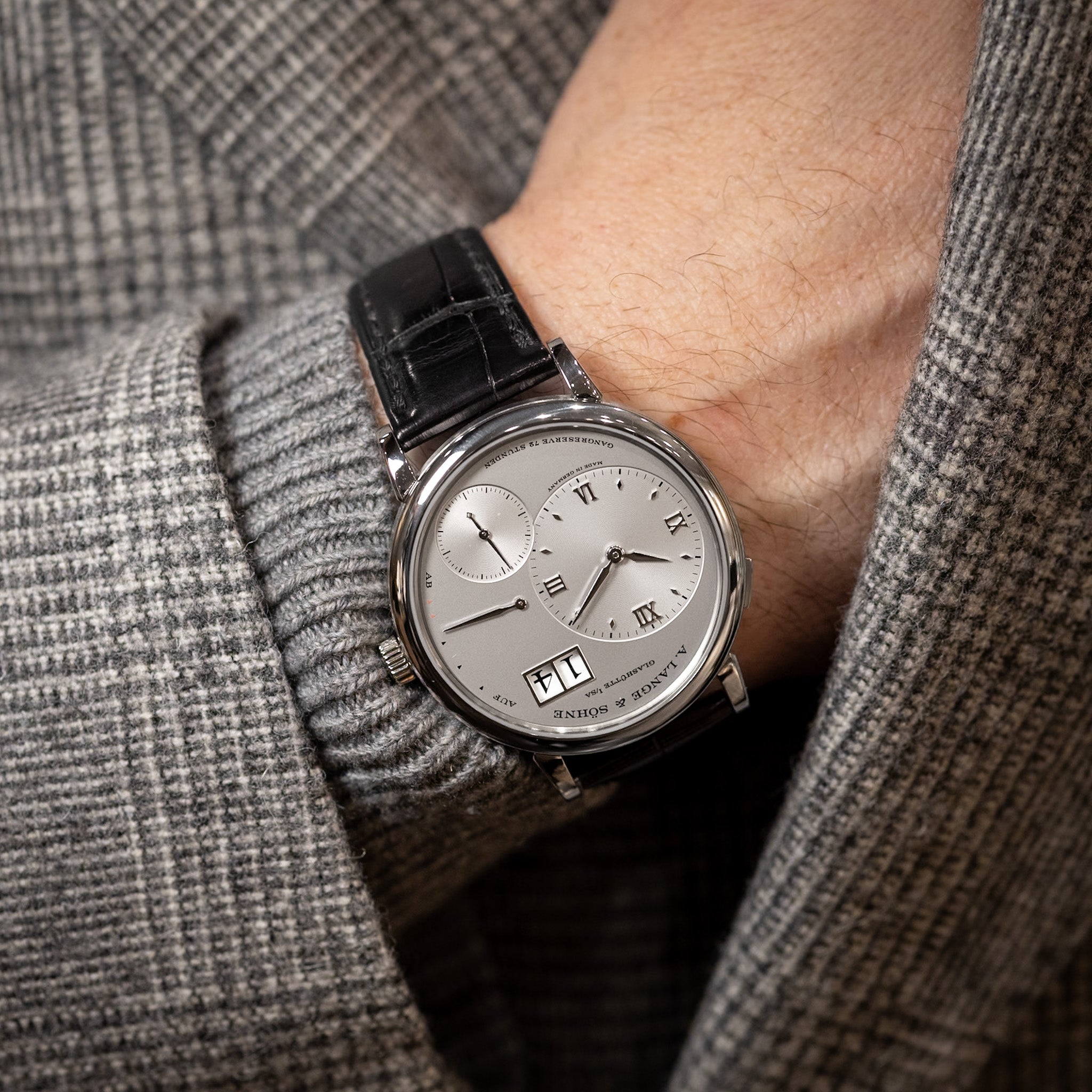 Luxury watch on a person's wrist with a gray suit background