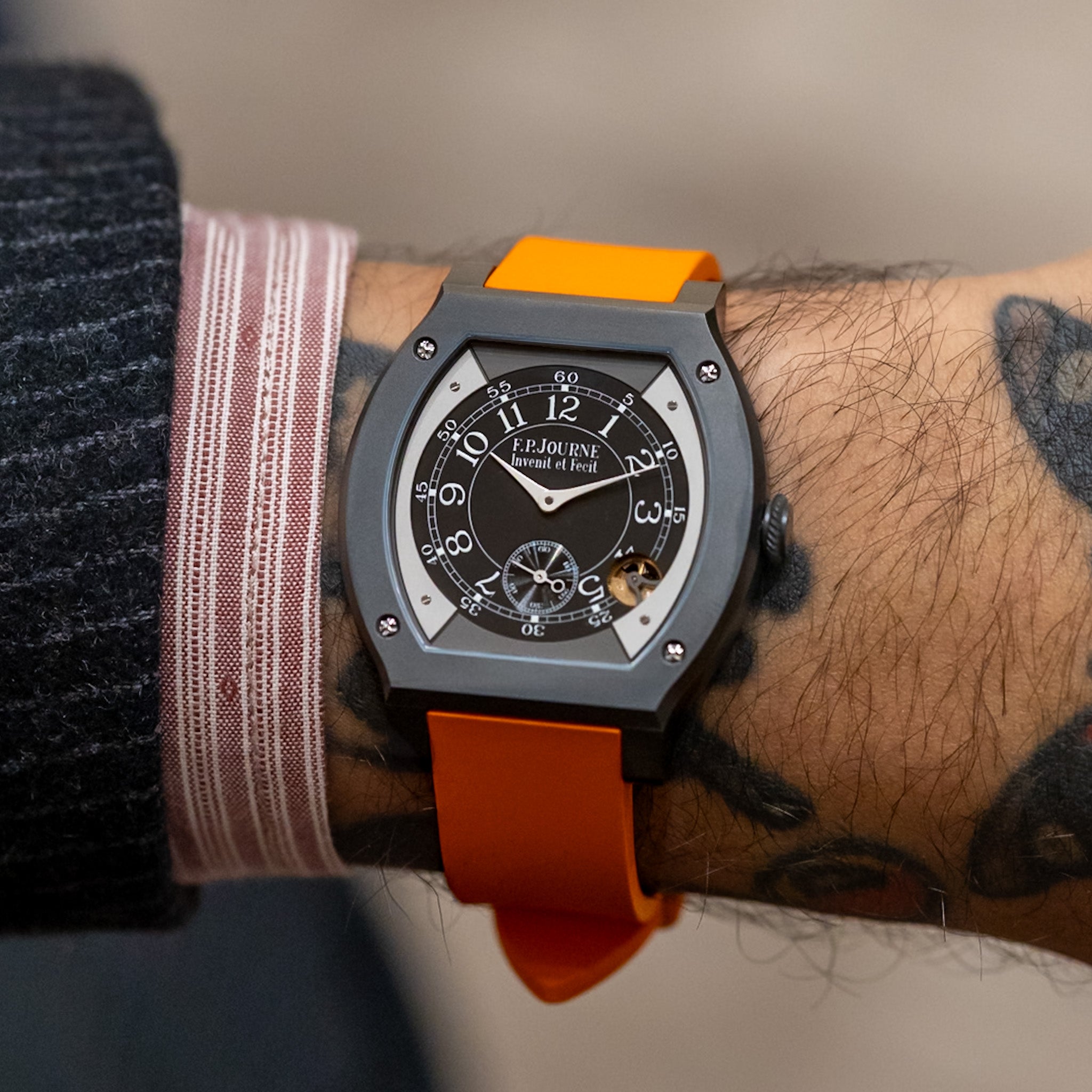 Watch with orange strap on a wrist with tattoos