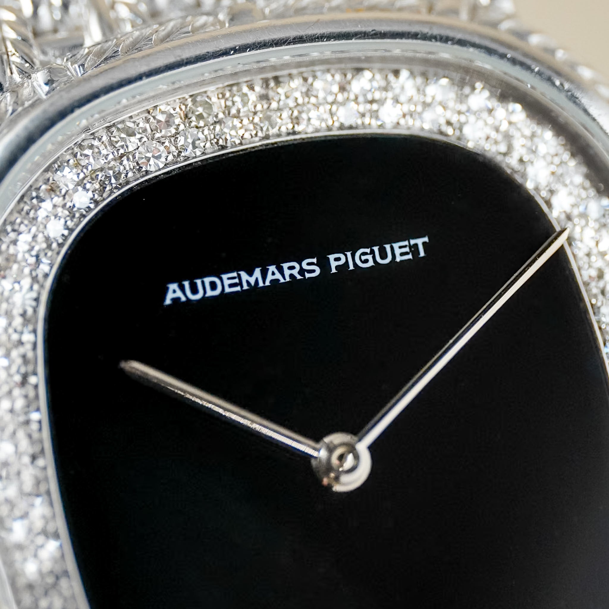 Close-up of an Audemars Piguet watch featuring a black dial, silver hands, and a diamond-encrusted bezel.