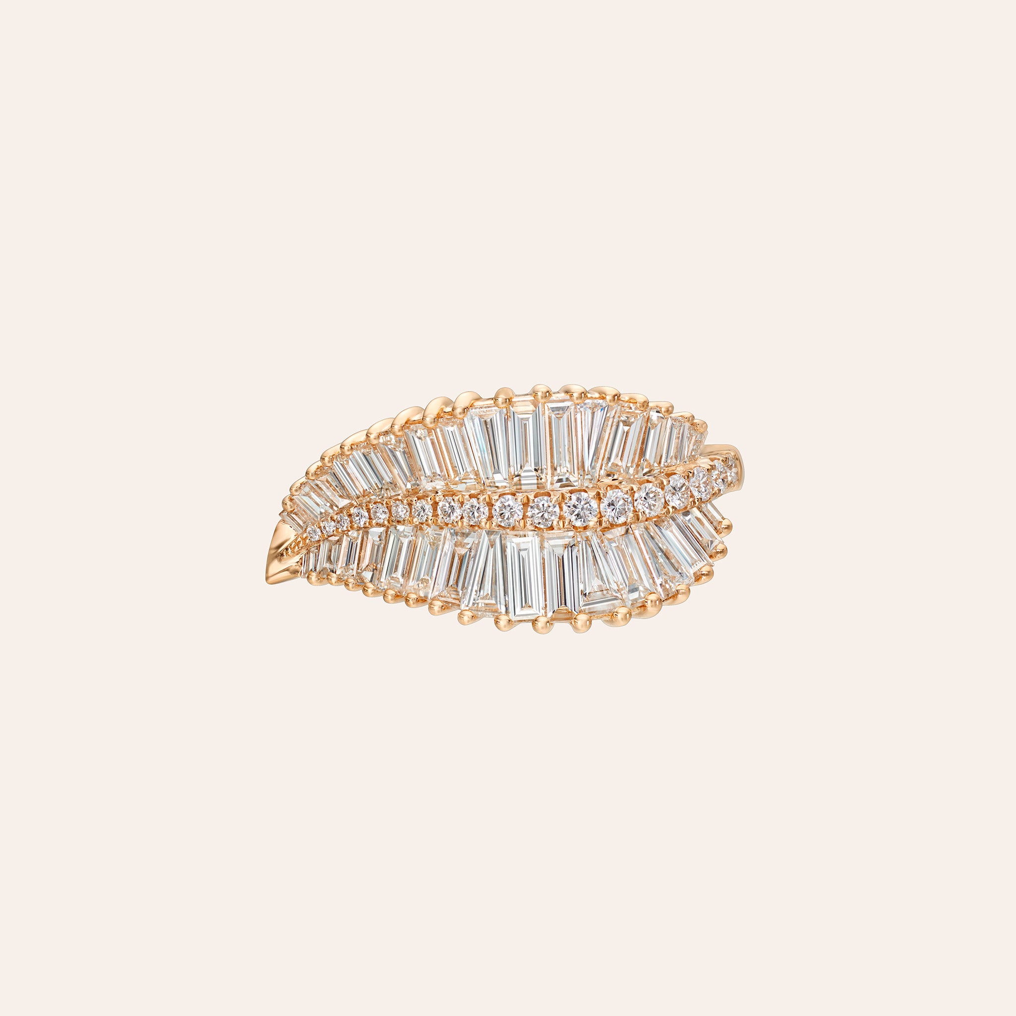 A rose gold leaf-shaped ring embellished with baguette and round clear stones, set against a solid light beige background.