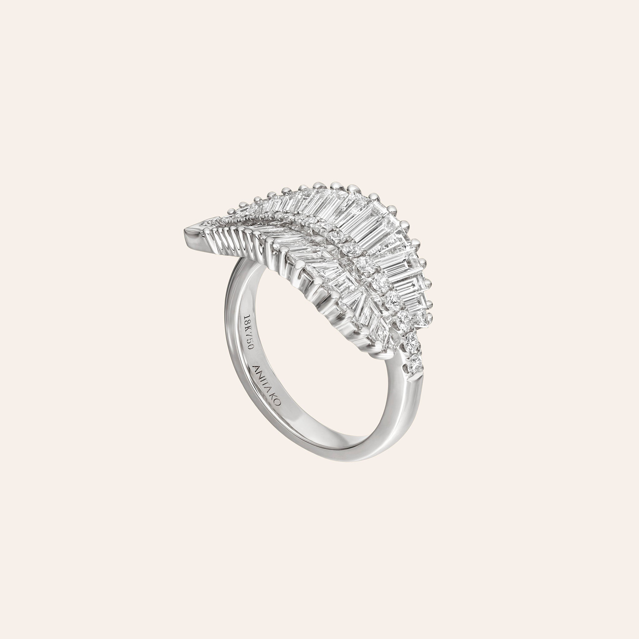 A white gold ring featuring a curved, leaf-like top set with baguette-cut clear stones, shown on a light beige background. The inner band is engraved with 'ANITA KO''.