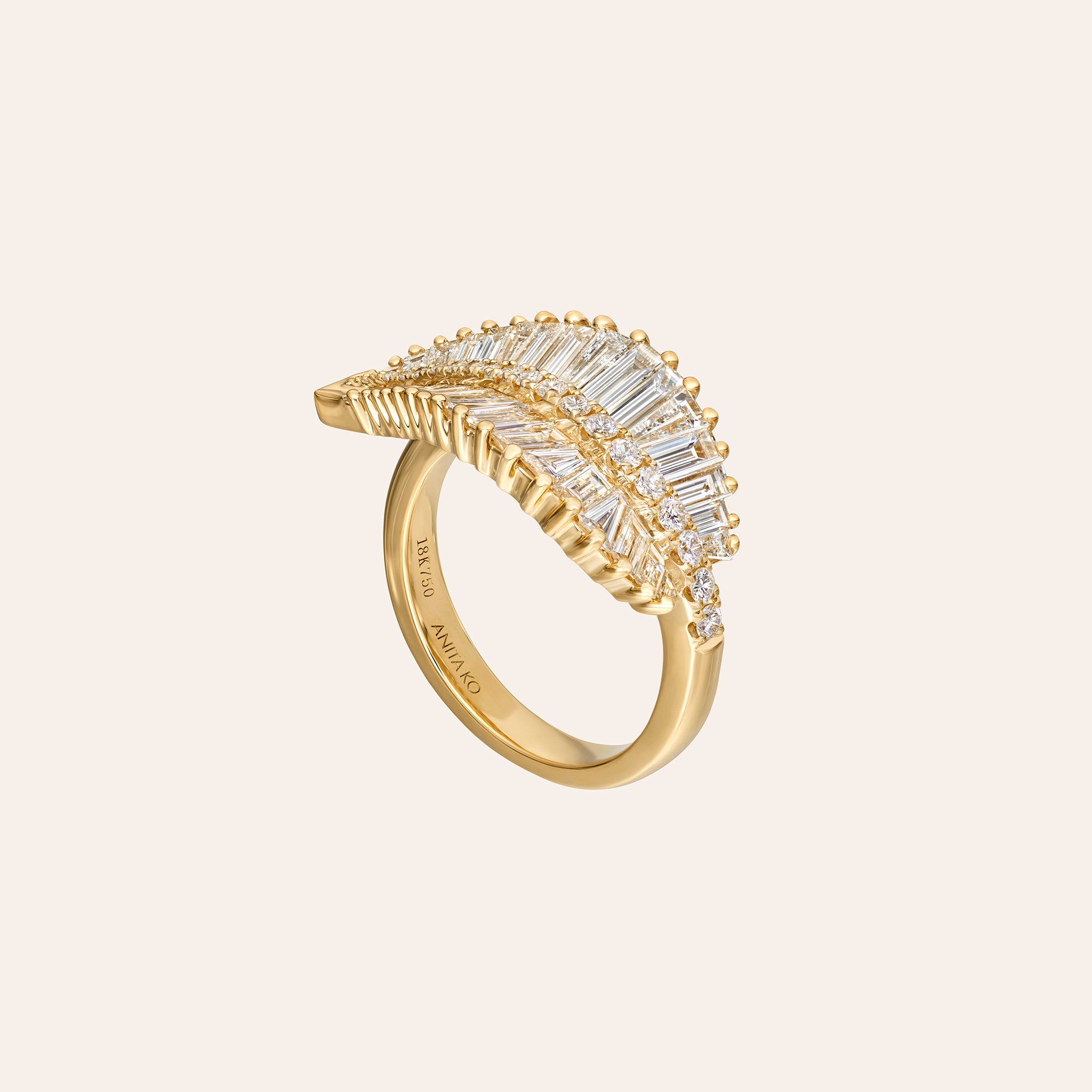 A gold ring featuring a leaf-shaped pavé setting with baguette and round clear stones, shown on a light beige background. The brand name 'ANITA KO' is engraved on the inner band.