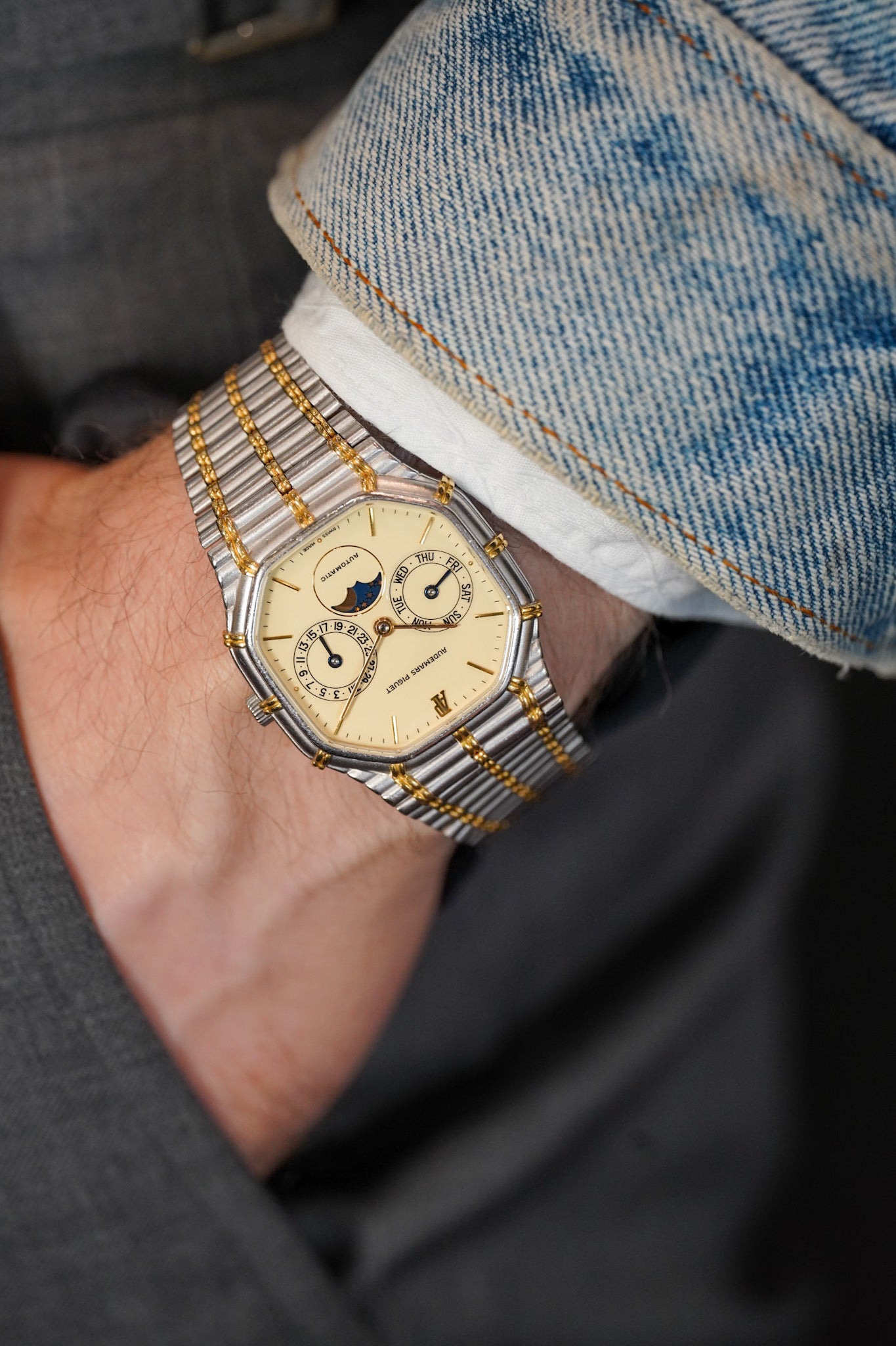 Close-up of a person wearing a detailed wristwatch with a gold and silver band.