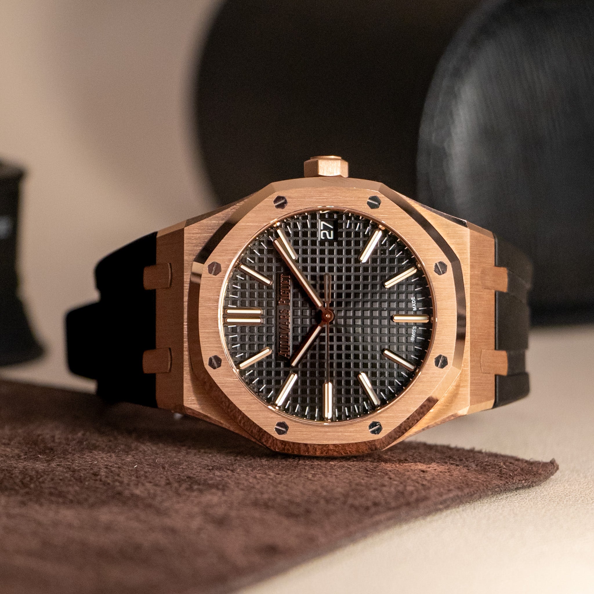 Rose gold Audemars Piguet Royal Oak with a black dial on a cream background