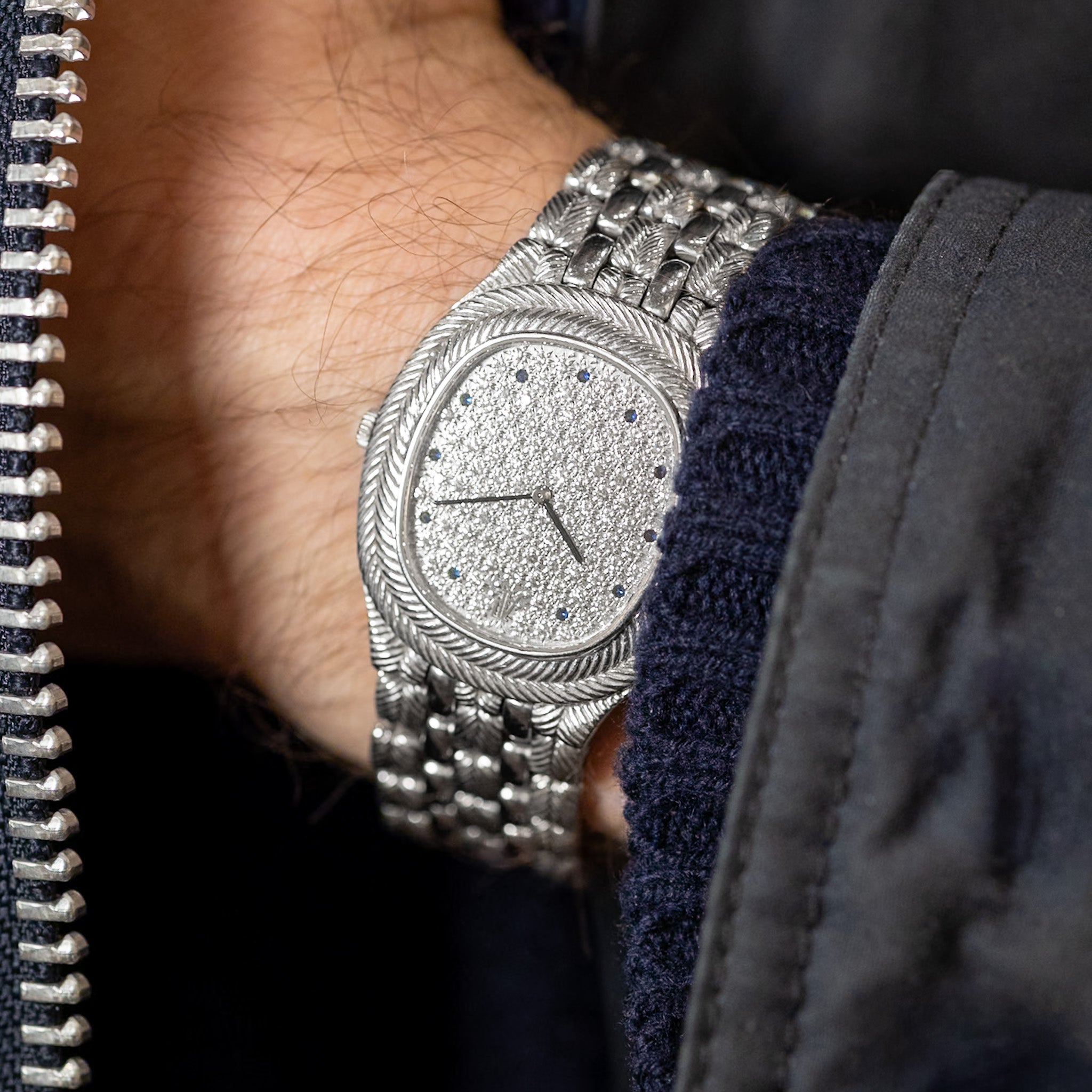 Silver wristwatch with detailed face on a person's wrist, close-up shot.