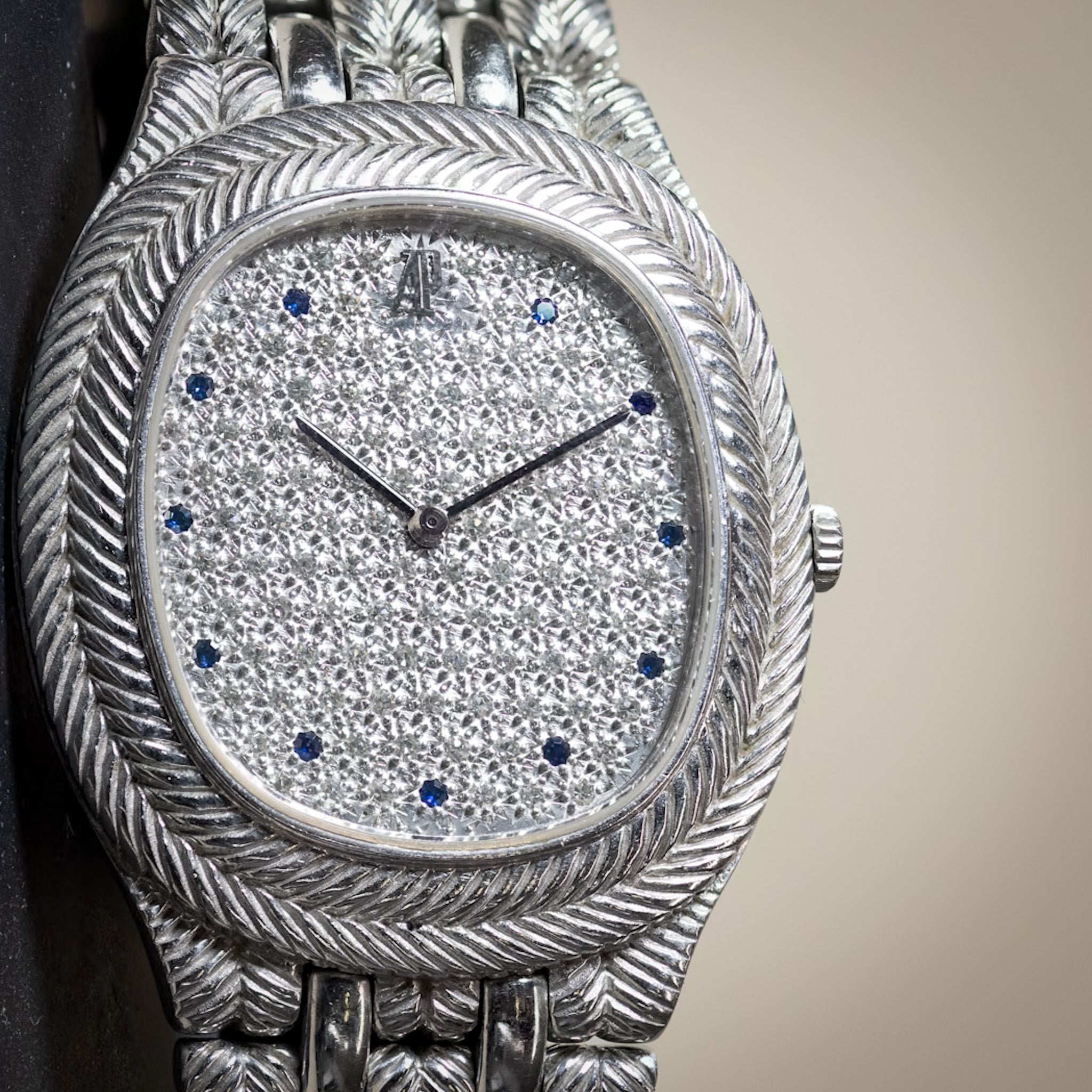 Silver watch with detailed design on a neutral background