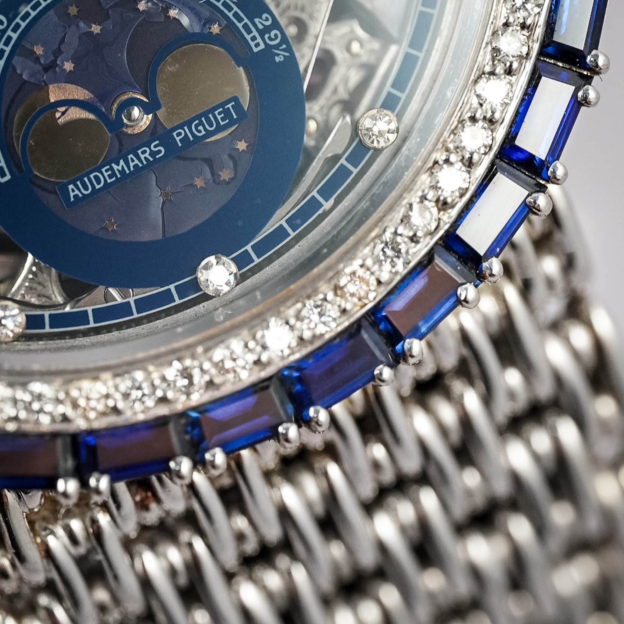 Close-up of a luxurious watch with diamond and gemstone details, featuring the brand 'Audemars Piguet'.