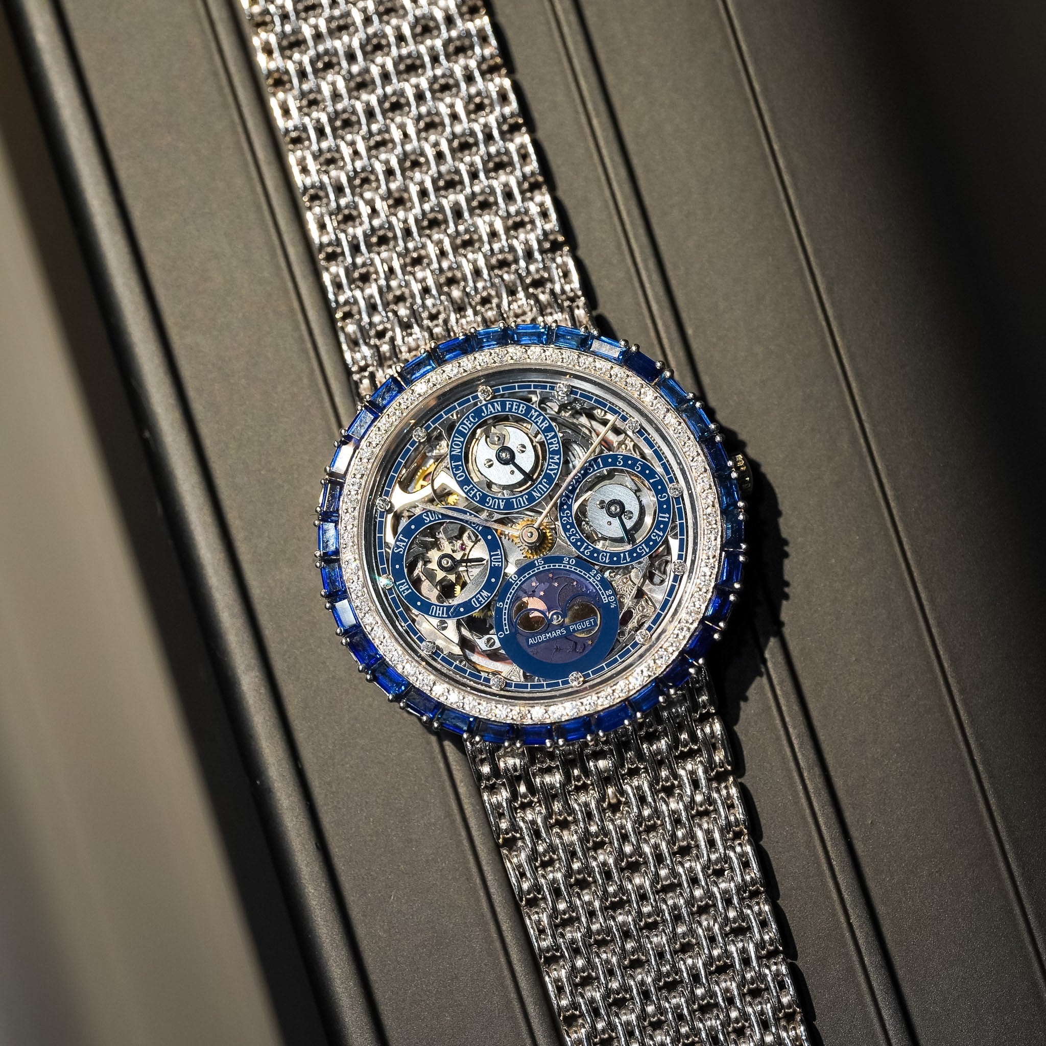 Luxury watch with intricate design and blue accents on a metallic band.