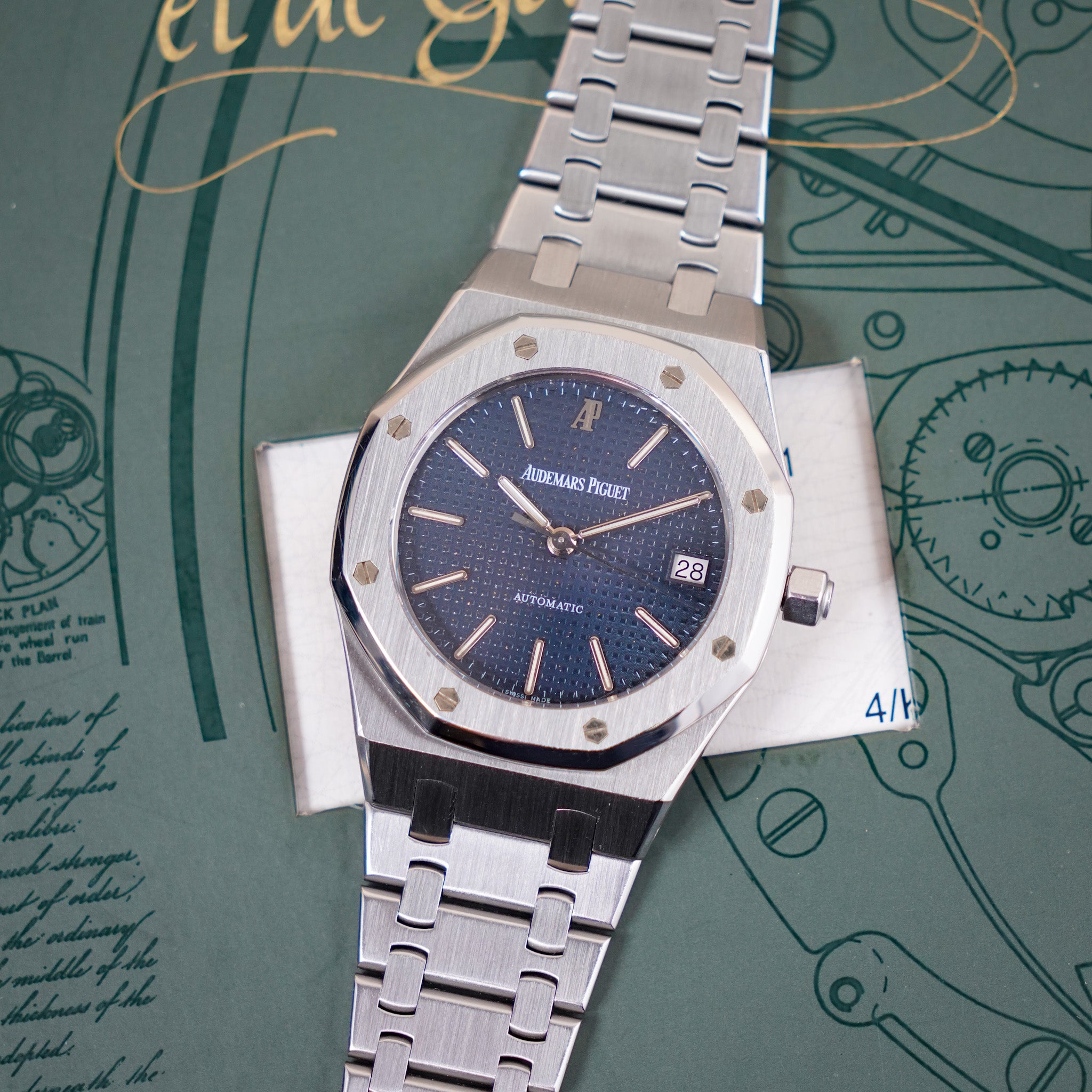 Silver watch with blue dial on a green background