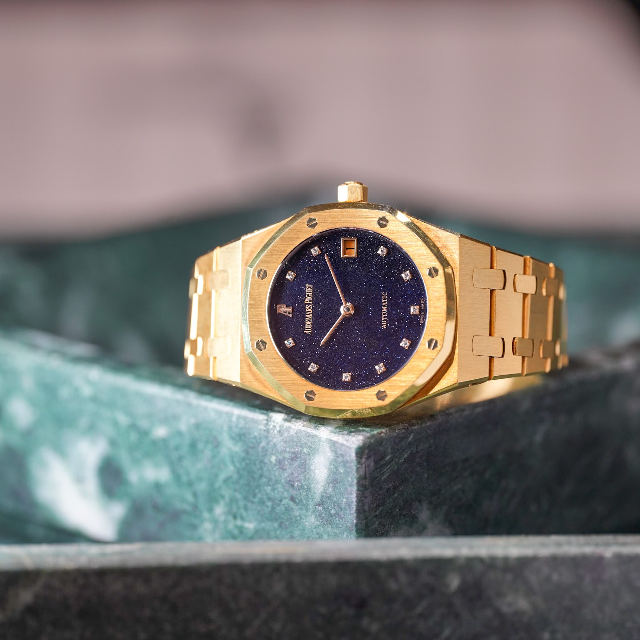 Gold watch with a dark blue face on a marble surface