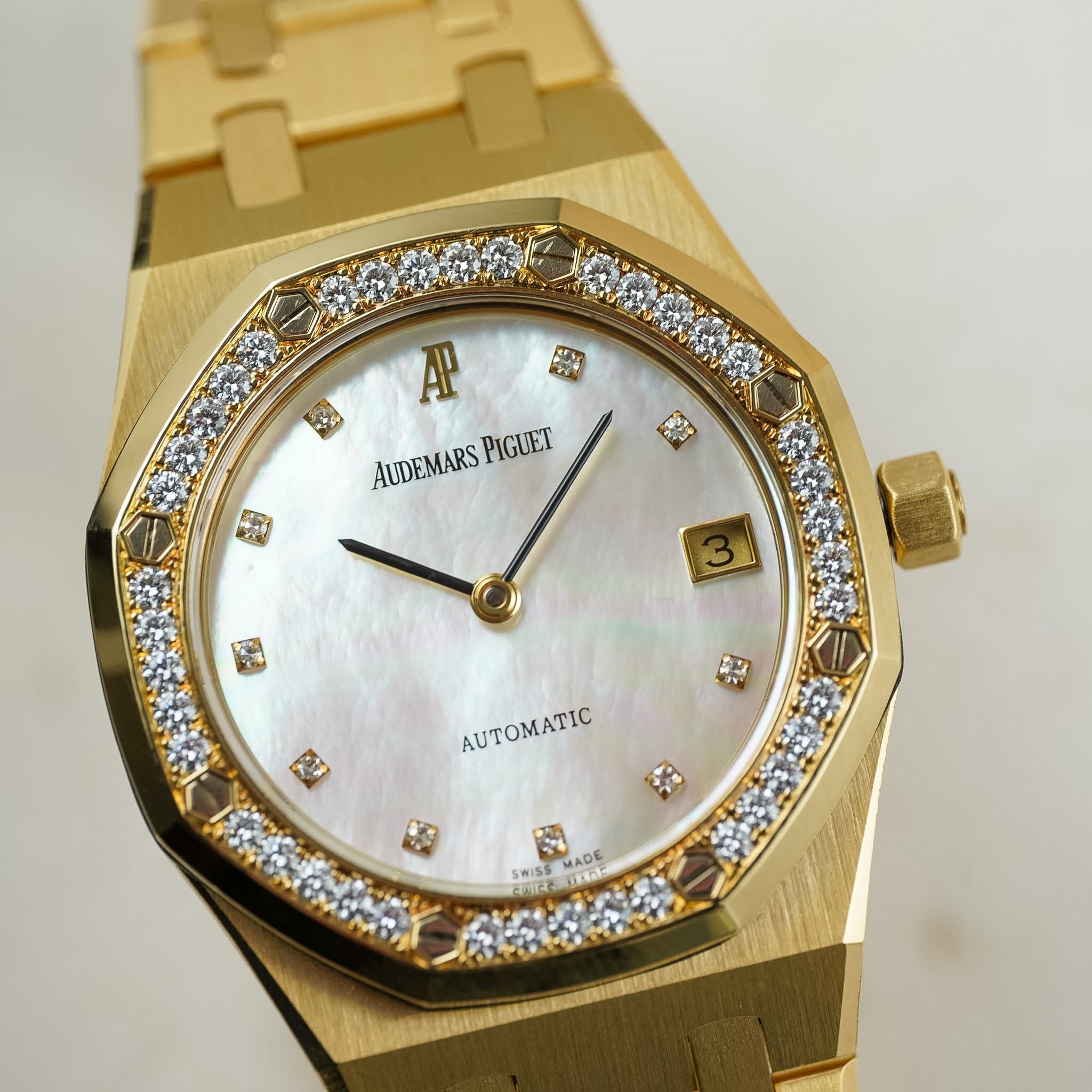Gold watch with diamond accents on a light background