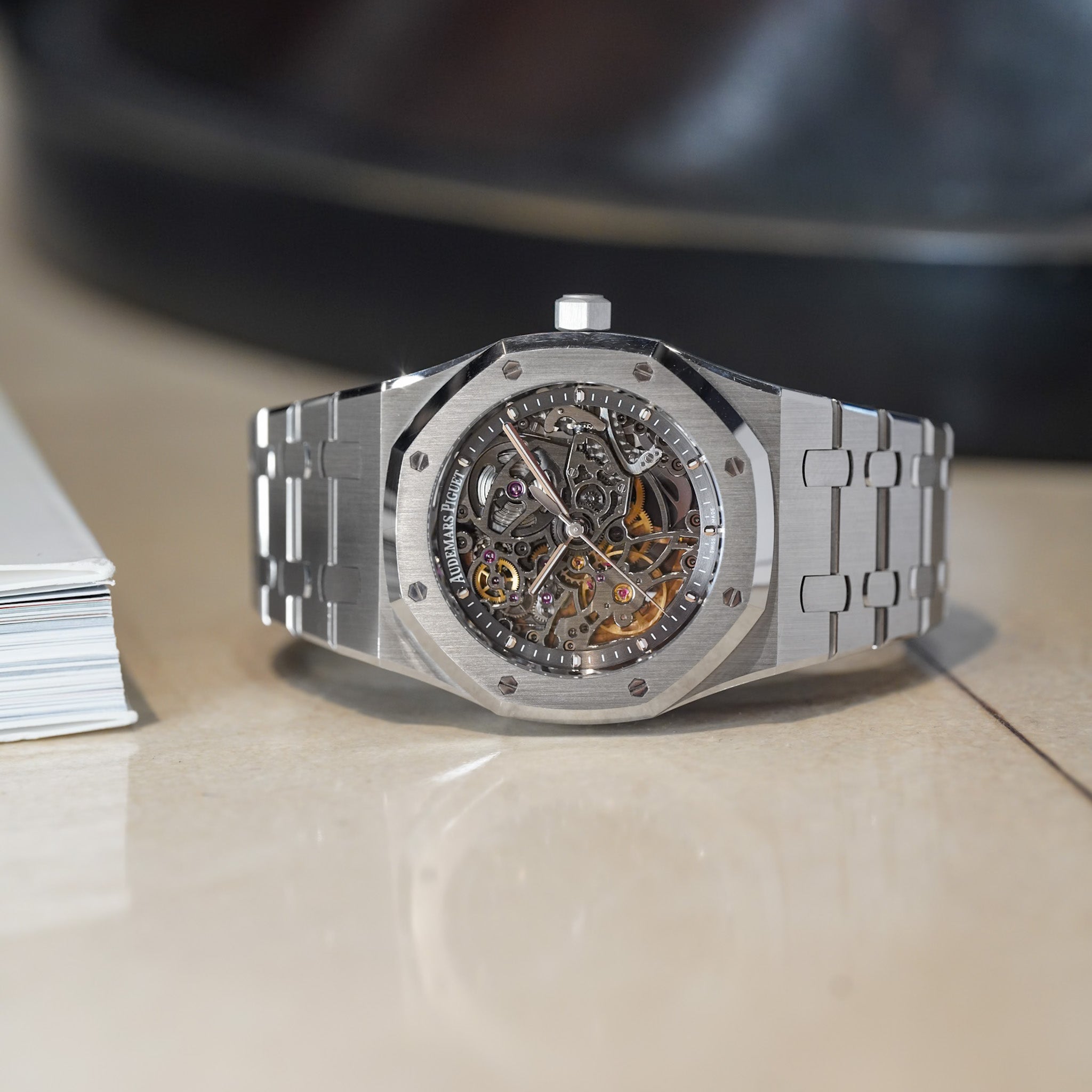 Silver watch with a detailed mechanism on a reflective surface