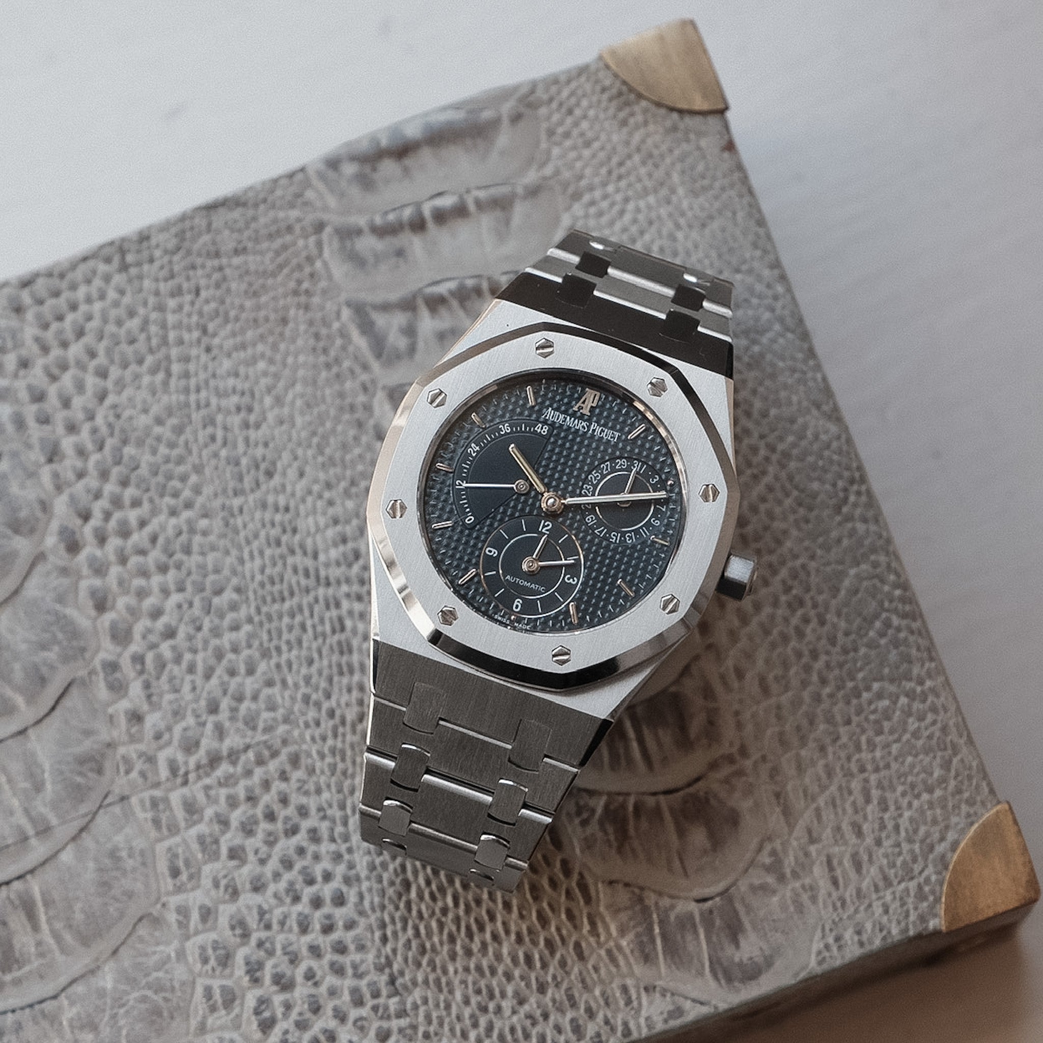 Silver watch with a detailed face on a textured surface