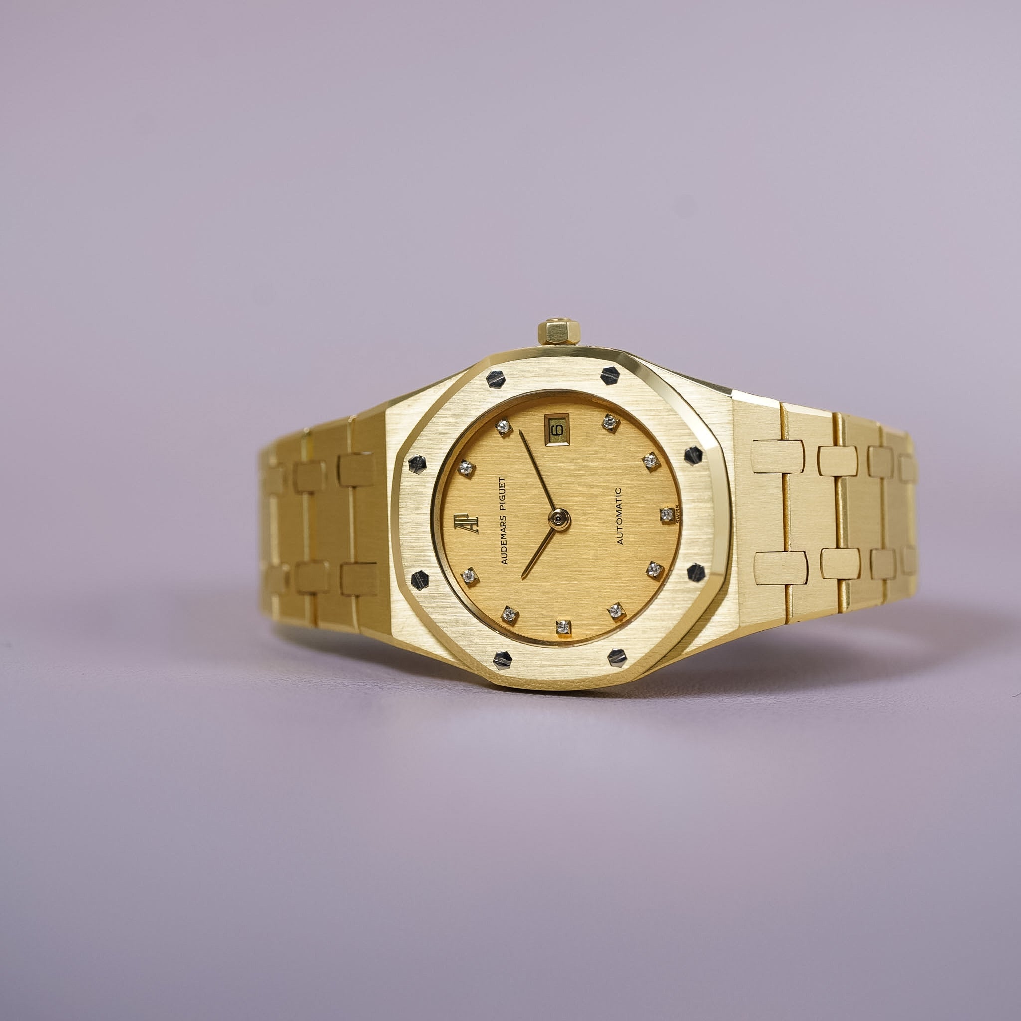 Gold watch with diamond accents on a light purple background
