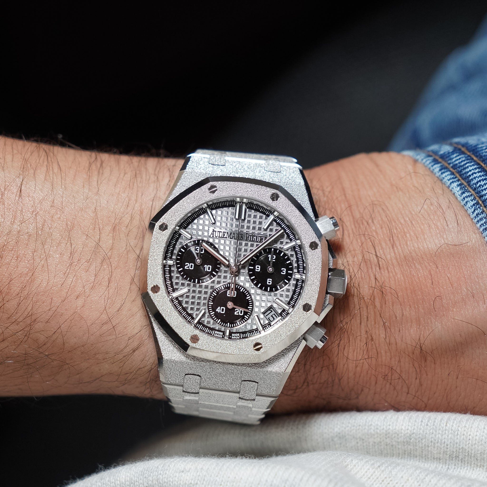 Silver watch with black face on a wrist against a dark background