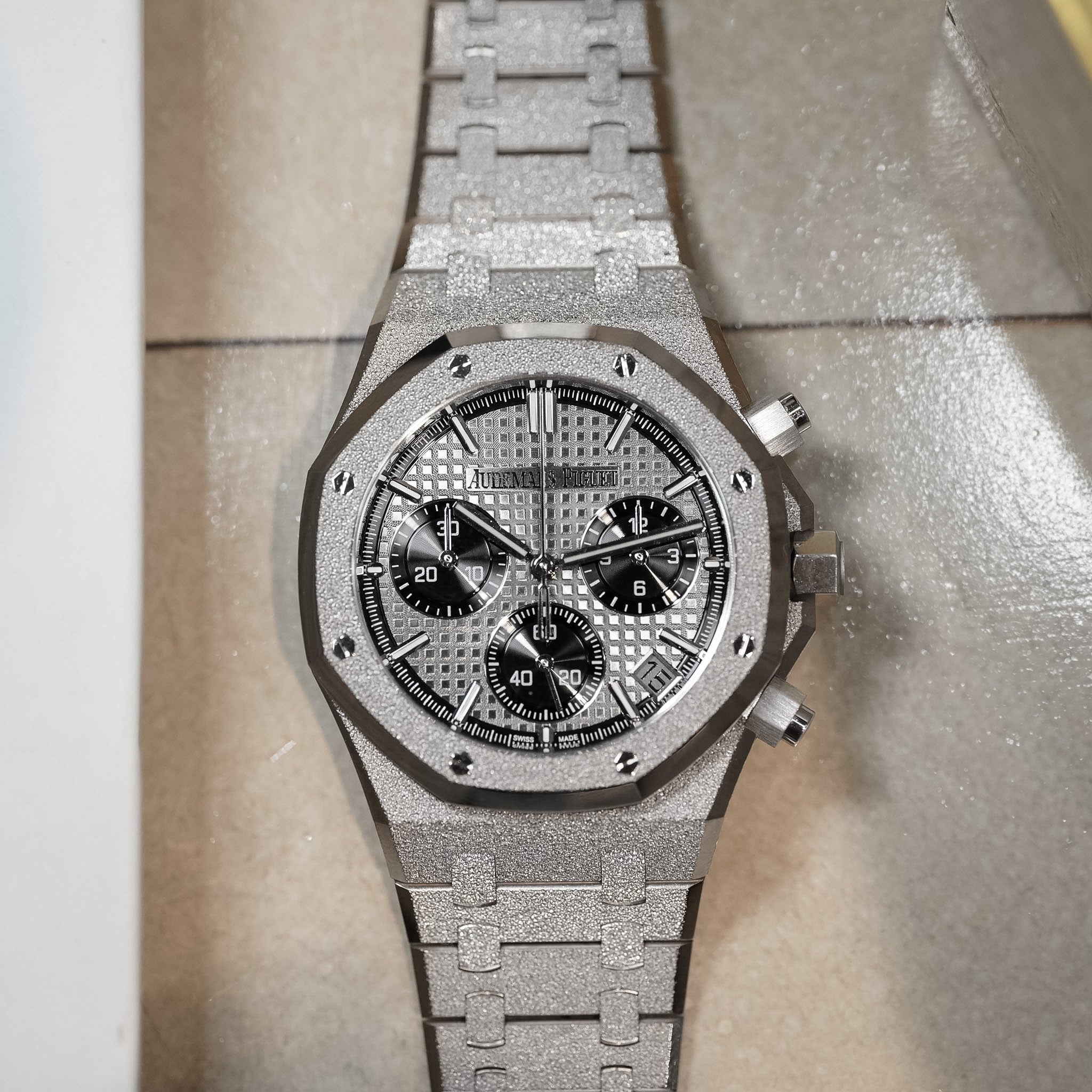 Silver watch with detailed face on a textured surface