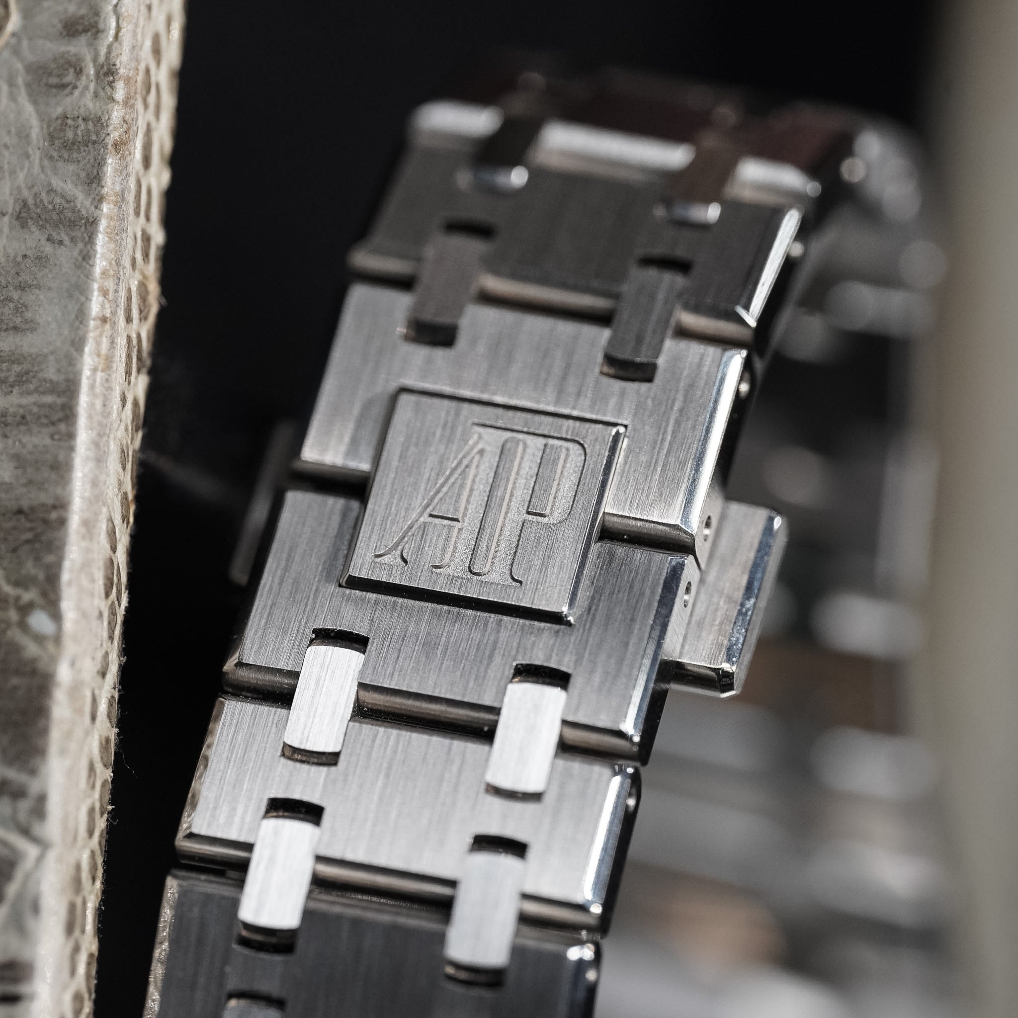 Close-up of a metallic watch band with a brand logo on a blurred background