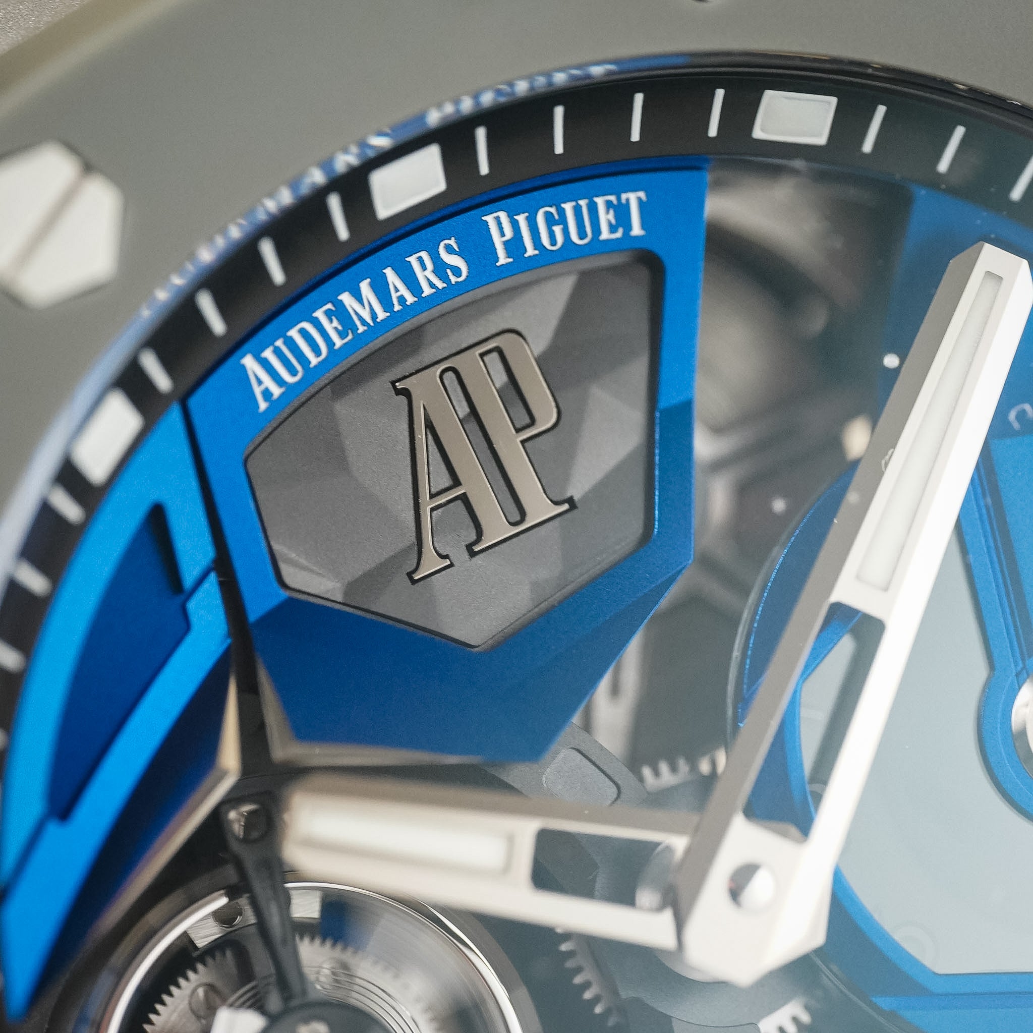 Close-up of an Audemars Piguet watch dial featuring a bright blue and gray faceted design, silver hands, and the brand's signature AP logo.