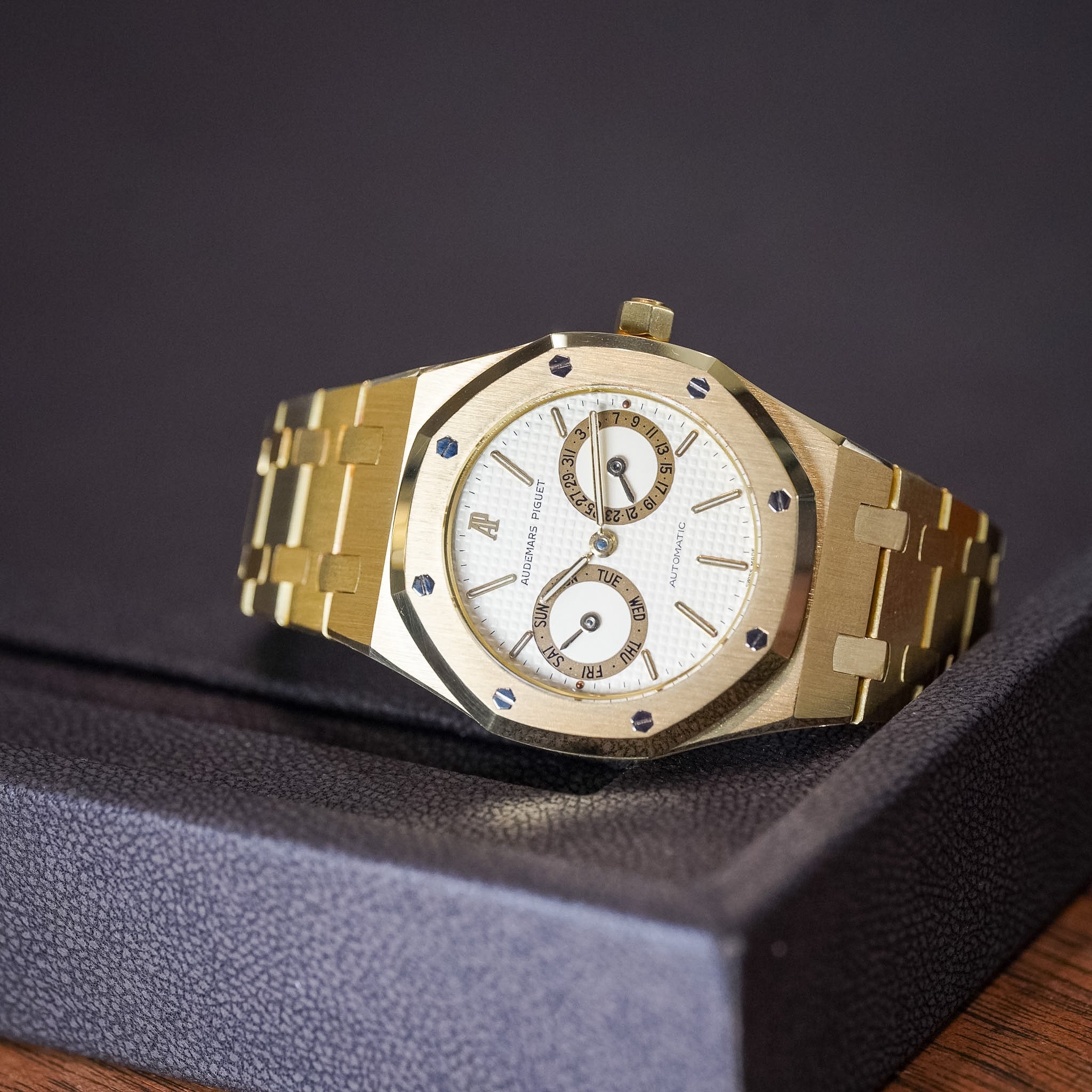Gold wristwatch with a detailed face on a dark surface