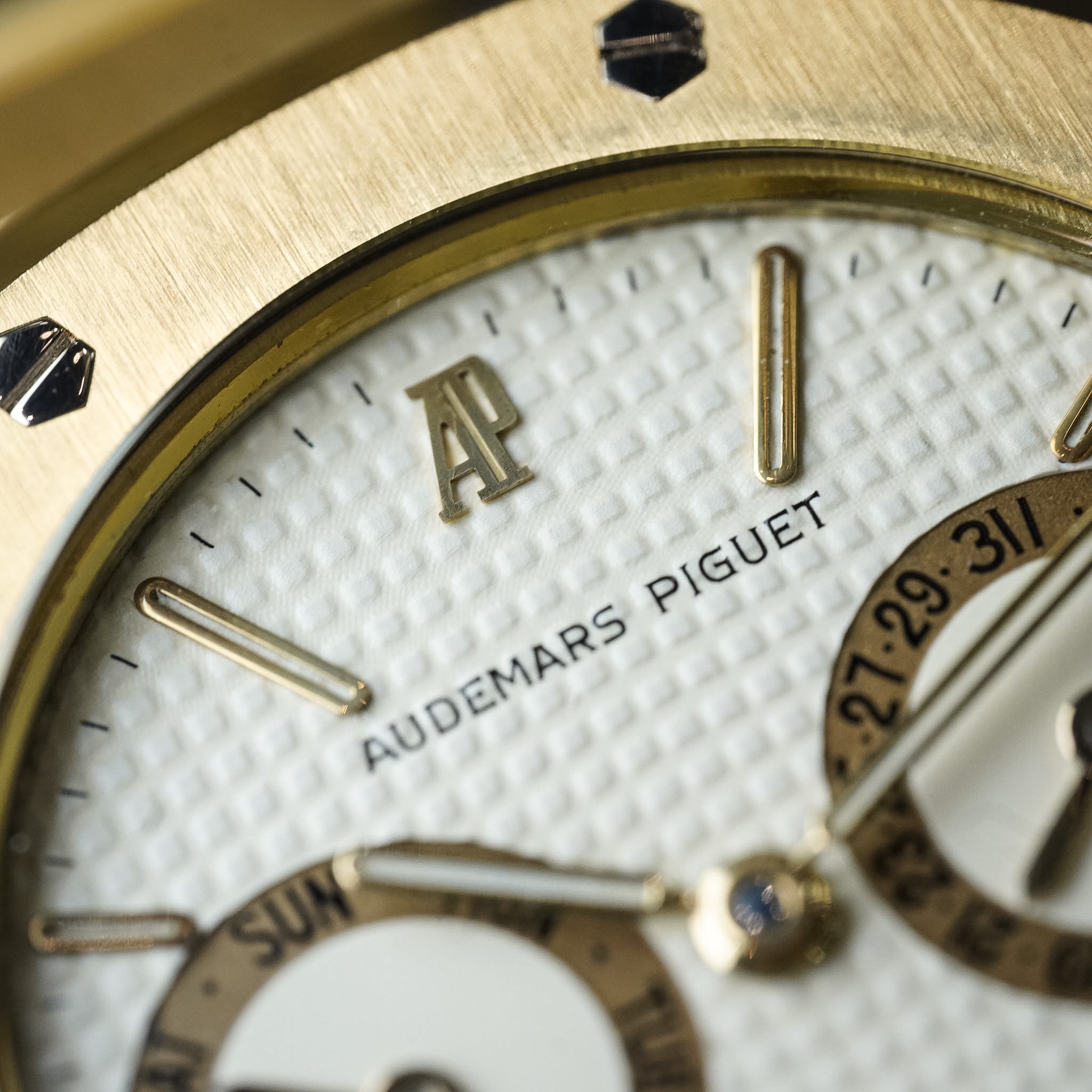 Close-up of an Audemars Piguet watch face with gold casing and white dial.