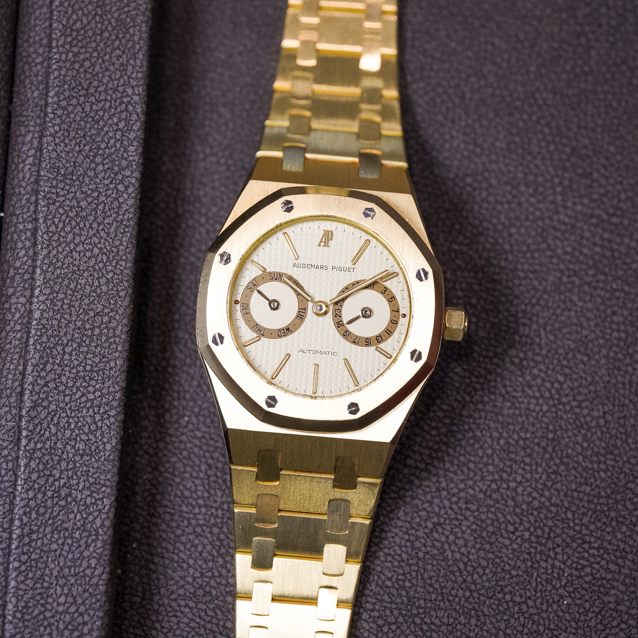 Gold wristwatch with a detailed face on a textured purple background