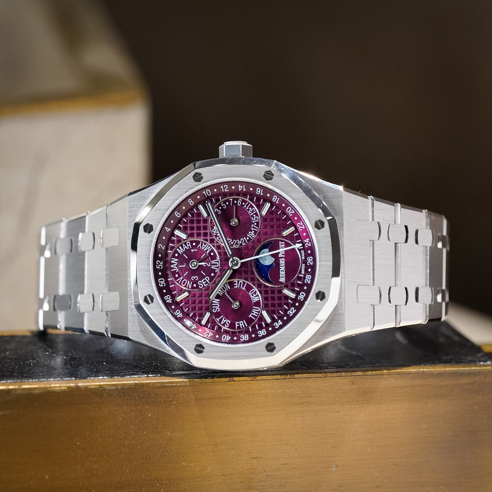 Silver watch with a purple face on a wooden surface