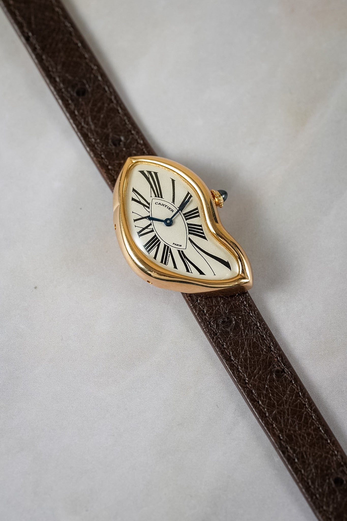 Gold wristwatch on a brown strap against a white background